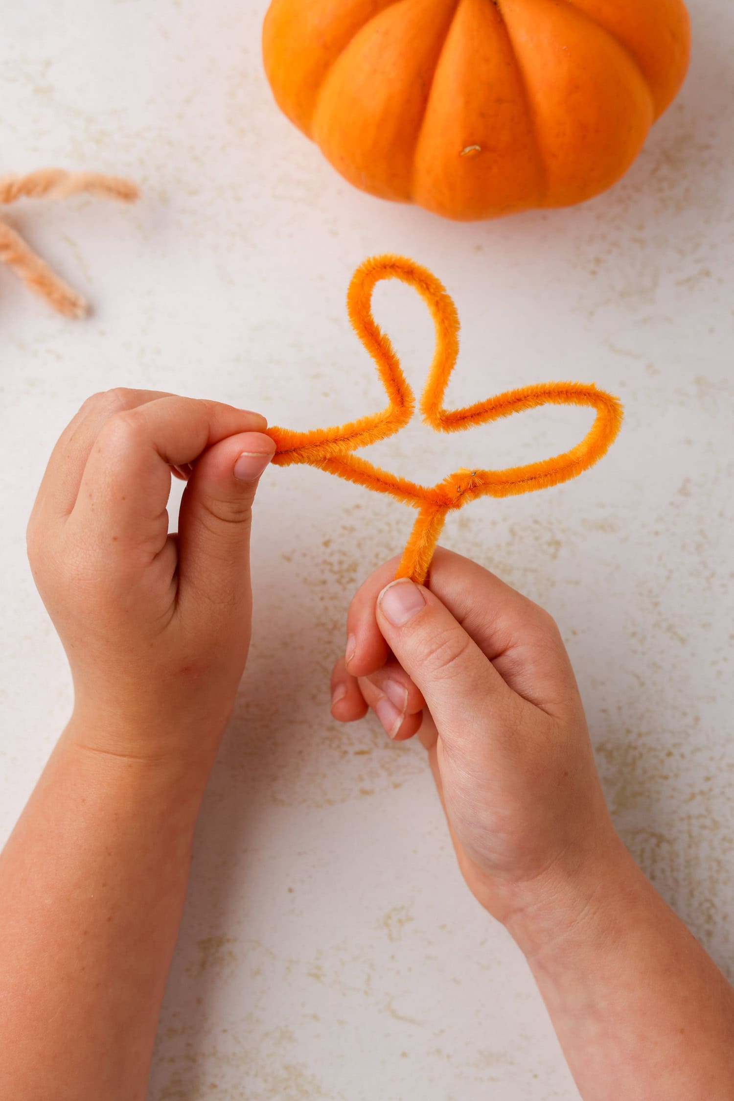 Press the right side of the mitten right in the middle towards the twisted part of the balloon. This will form the middle and right toes. The shape should look similar to a 3-leaf clover and then begin twisting pipe cleaners for the Turkey Craft