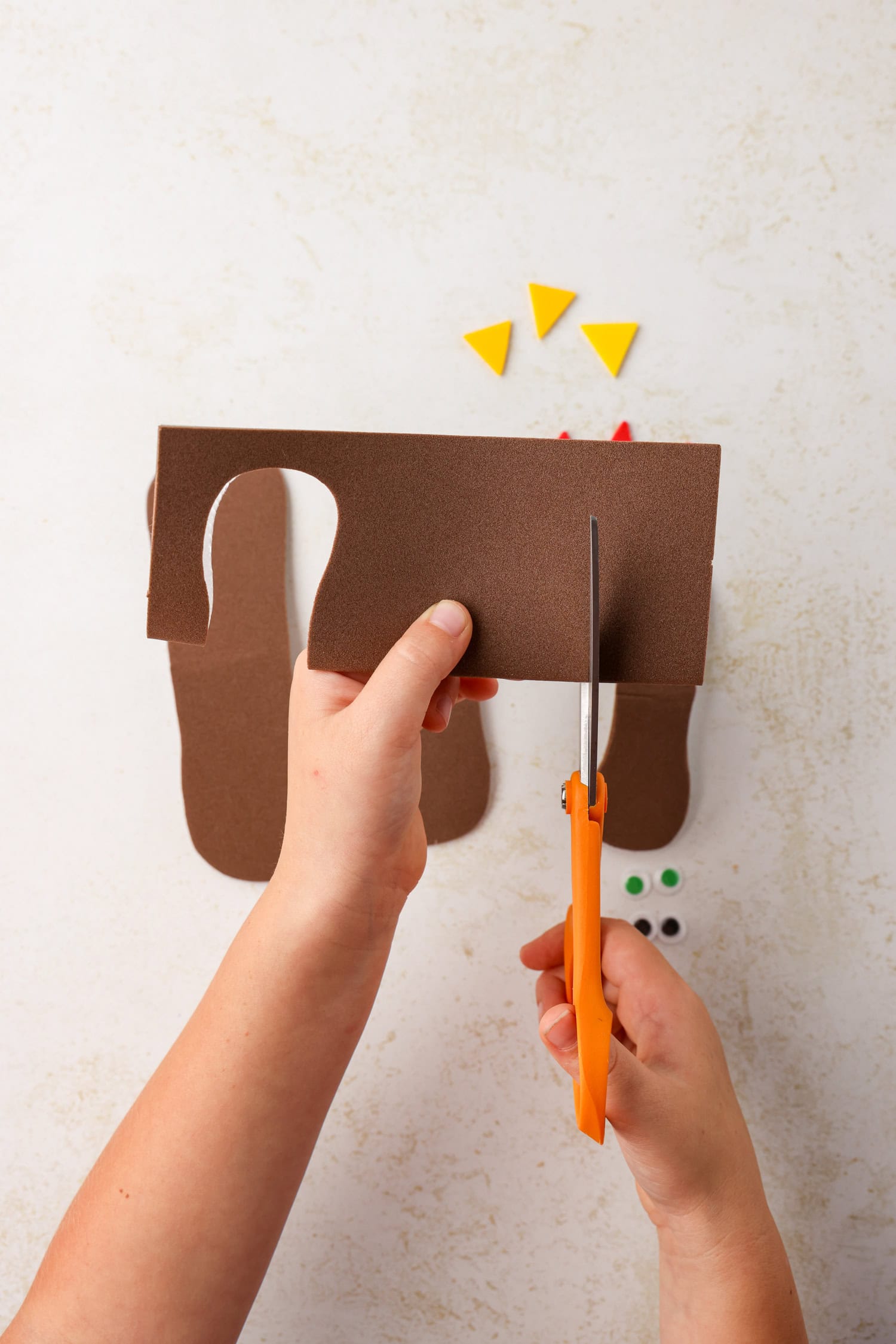 Cutting peanut-shaped pieces from foam for Mini Pumpkin Turkey Craft