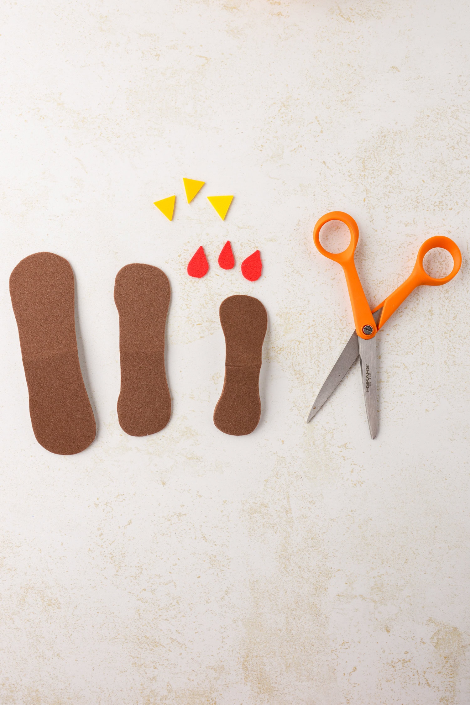 Peanut-shaped foam pieces with yellow and red face foam pieces for Mini Pumpkin Turkey Craft