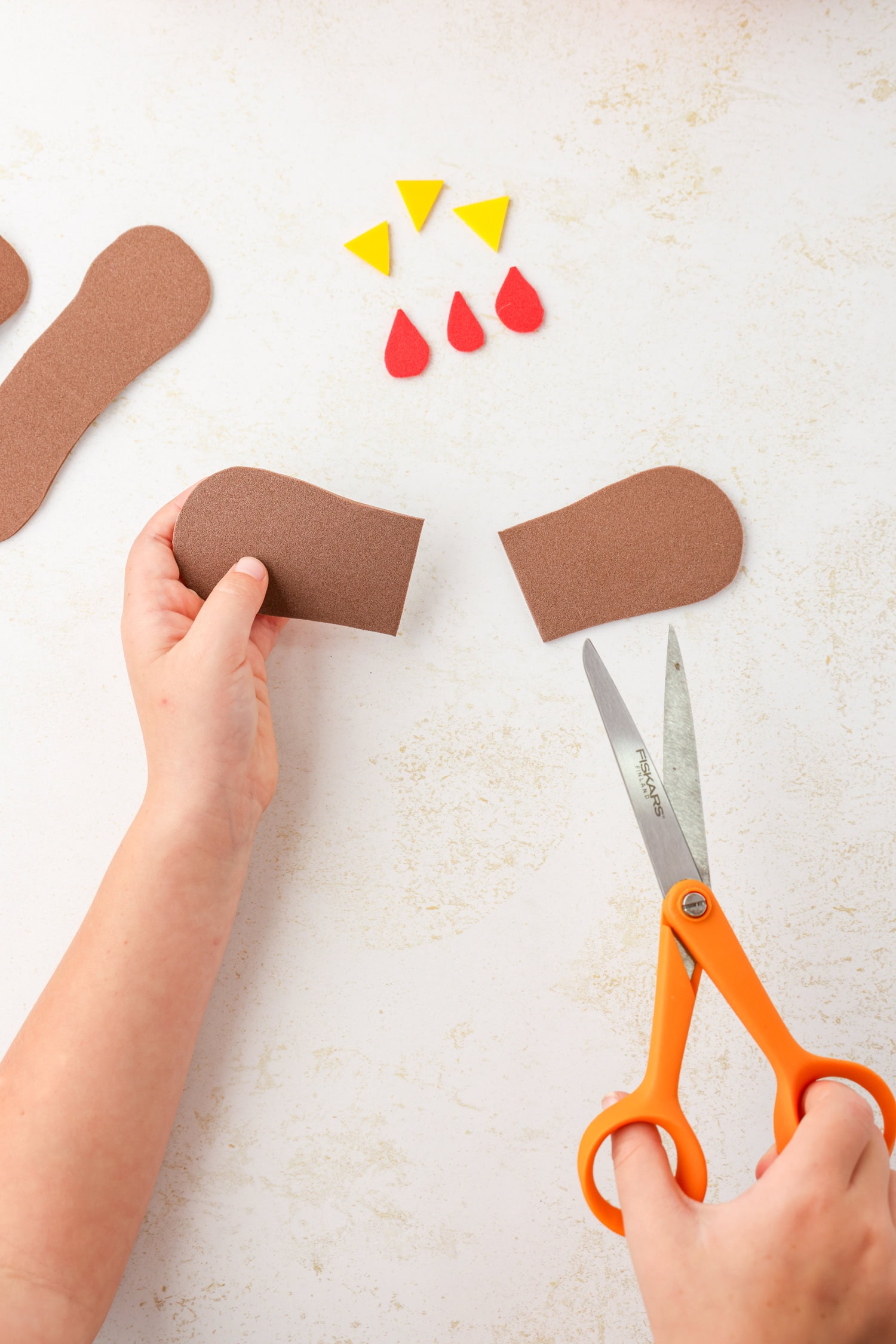 Cutting brown foam pieces for Mini Pumpkin Turkey Craft