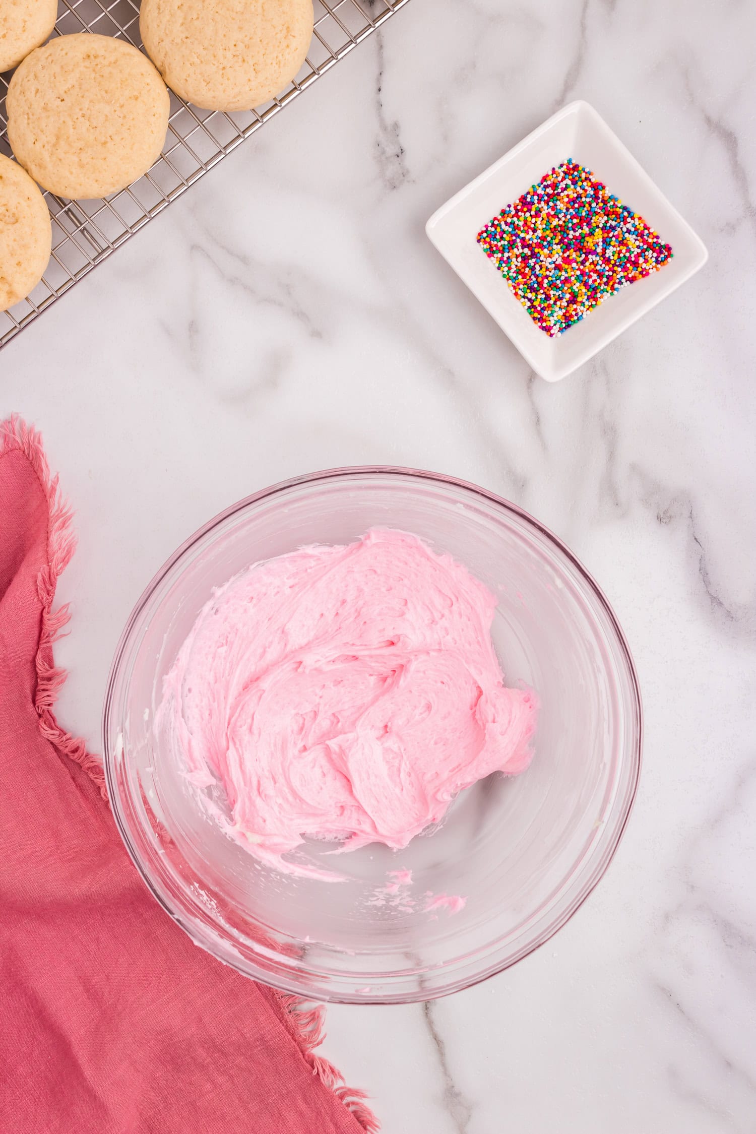 Homemade frosting in glass bowl with sprinkles to add in shallow dish