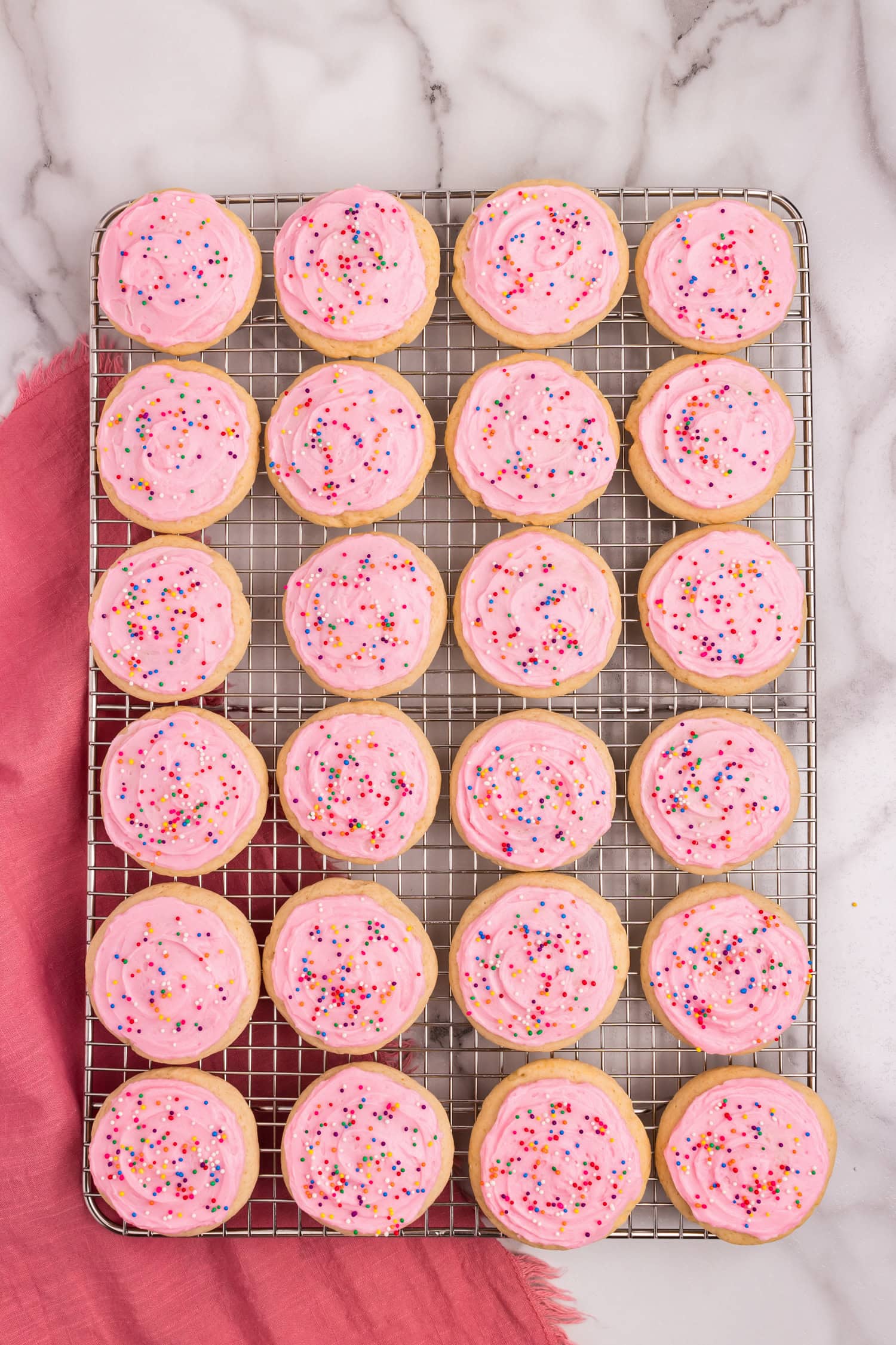 Sour Cream Cookies frosted with homemade frosting topped with colorful sprinkles on wire cooling rack