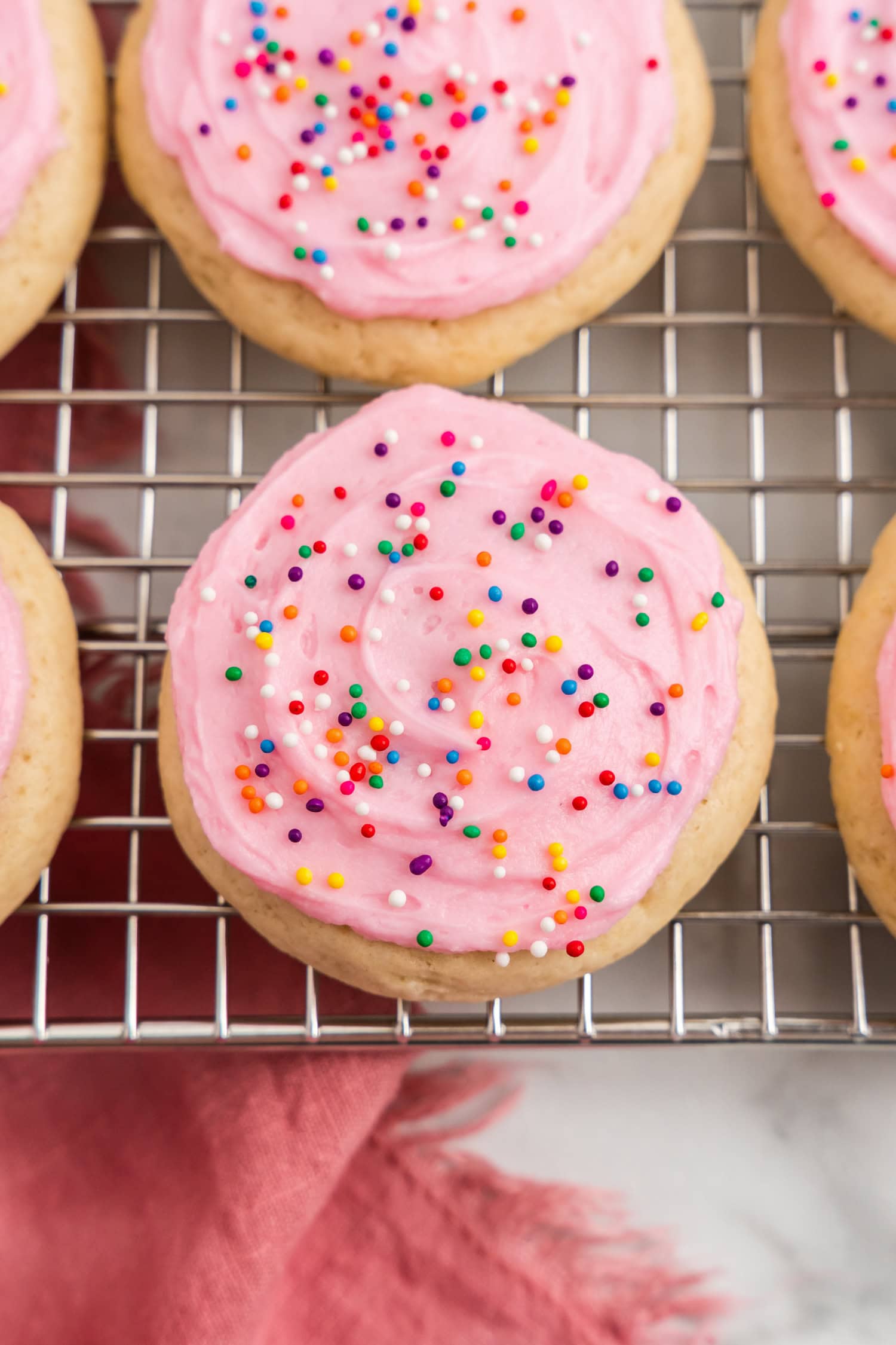 Frosted Sour Cream Cookies with sprinkles on cooling rack