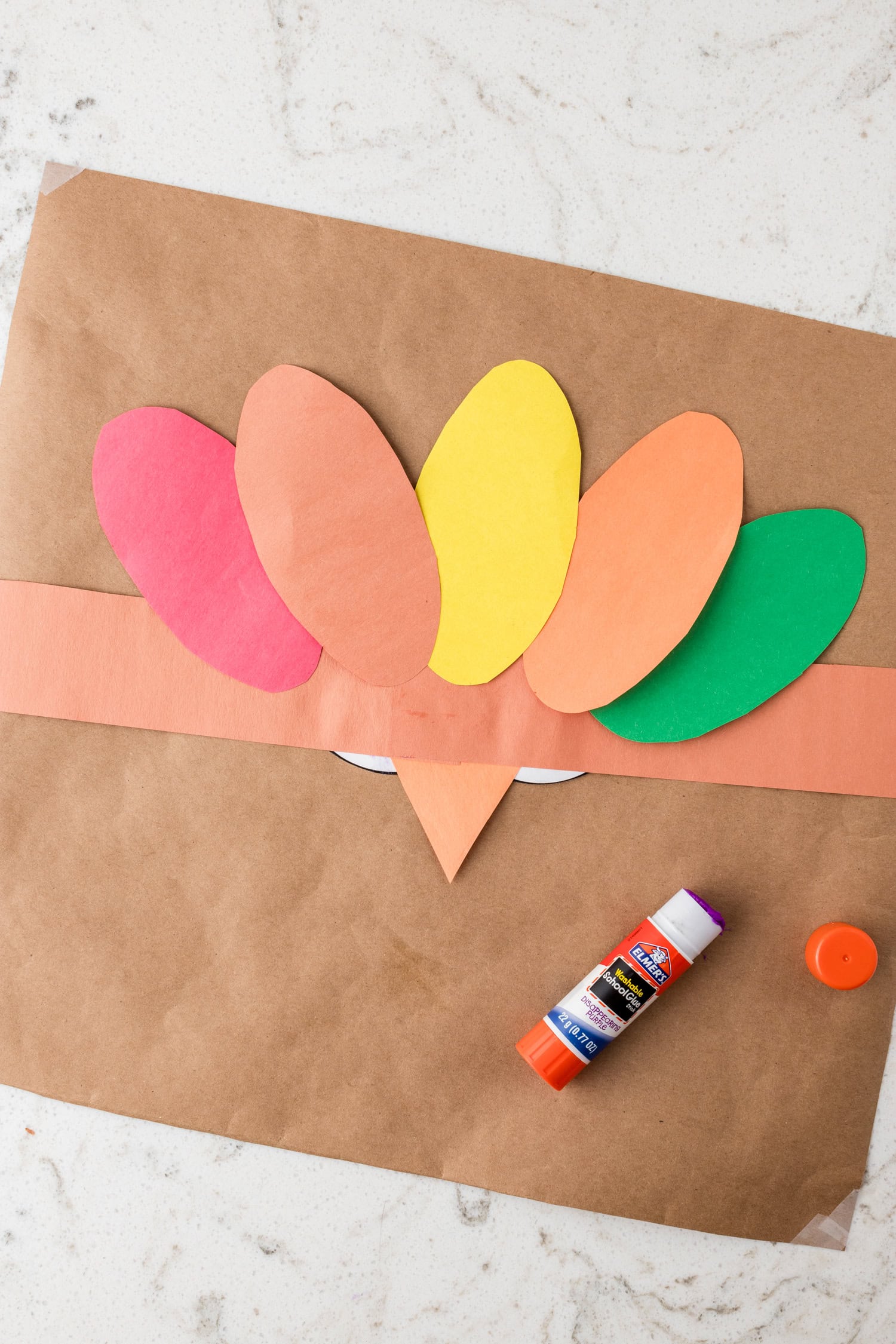 Gluing construction paper feathers to the underside of the Turkey Headband Craft