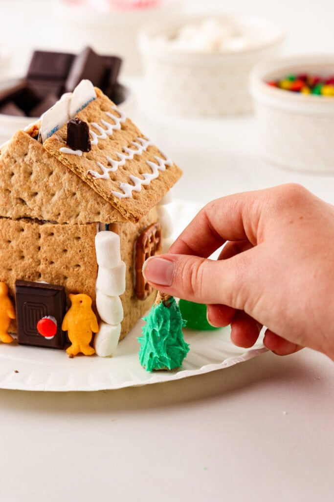 Overhead picture of hand placing a frosted bugle as a tree onto the paper plate.