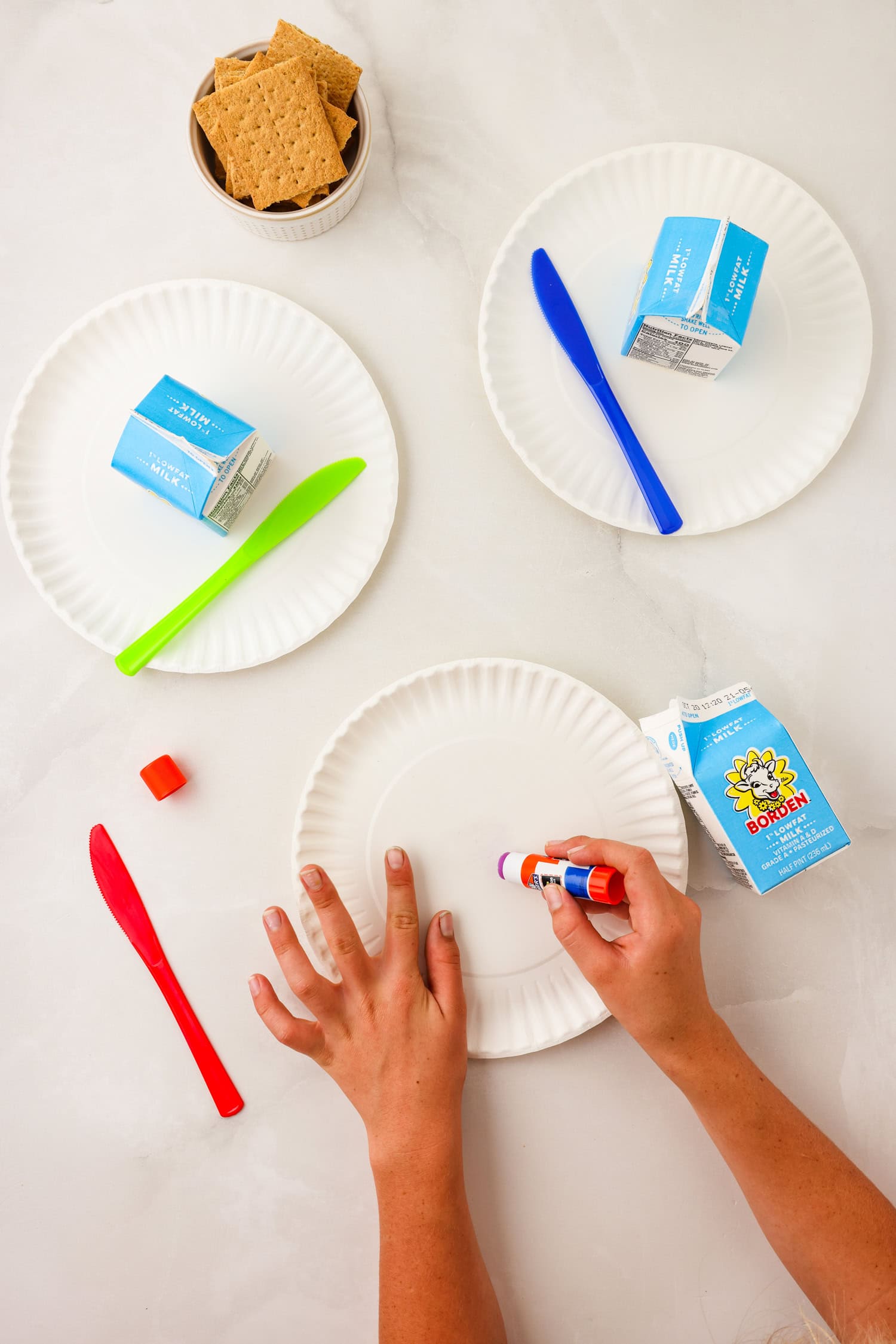 Overhead picture of hands putting glue on paper plate.