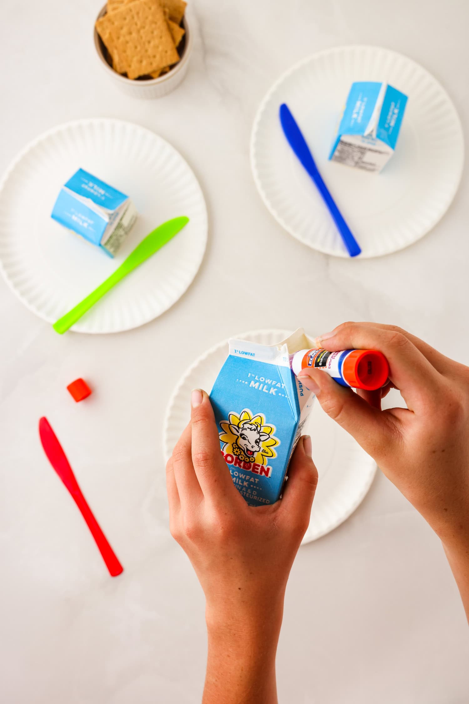 Overhead picture of hands applying glue to the opening of the milk carton.