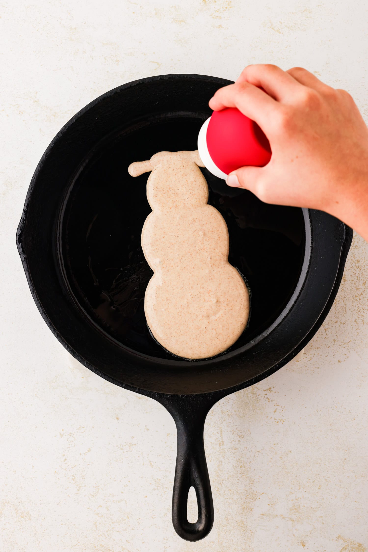 Hand squeezing frosting bulb to make bottom of snowmans hat.