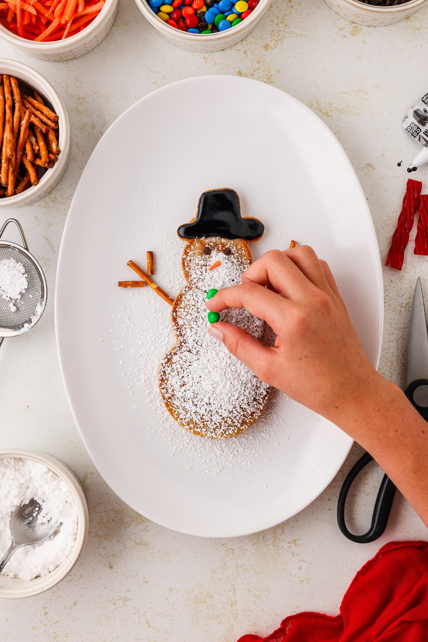 Snowman pancake with m&m buttons being put on it.