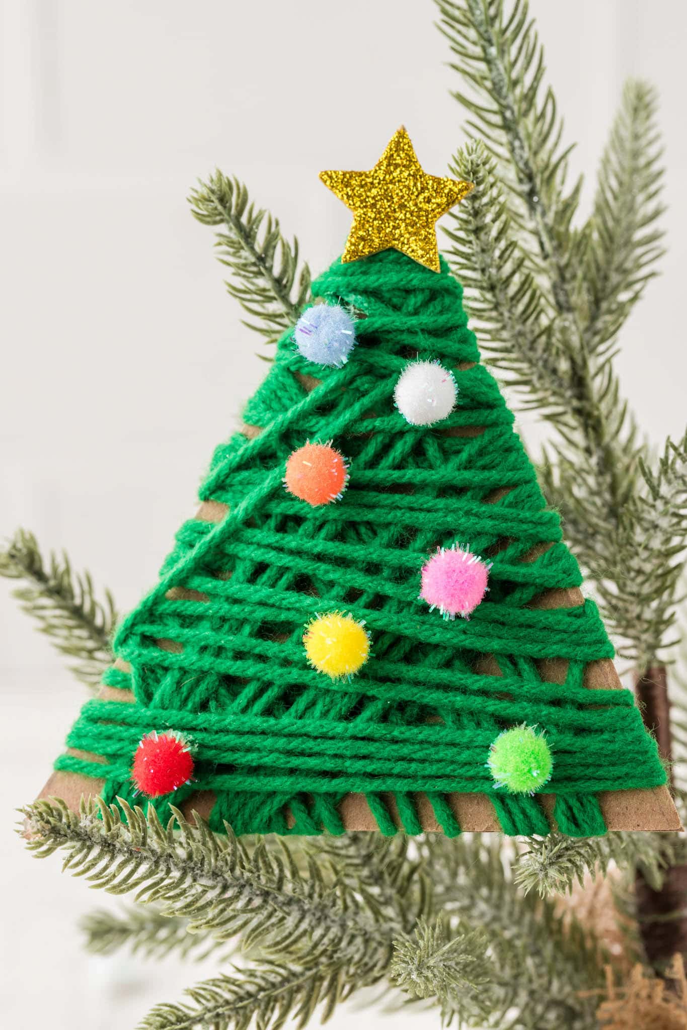 Close up picture of completed Yarn Wrapped Christmas Trees positioned on a real Christmas tree.