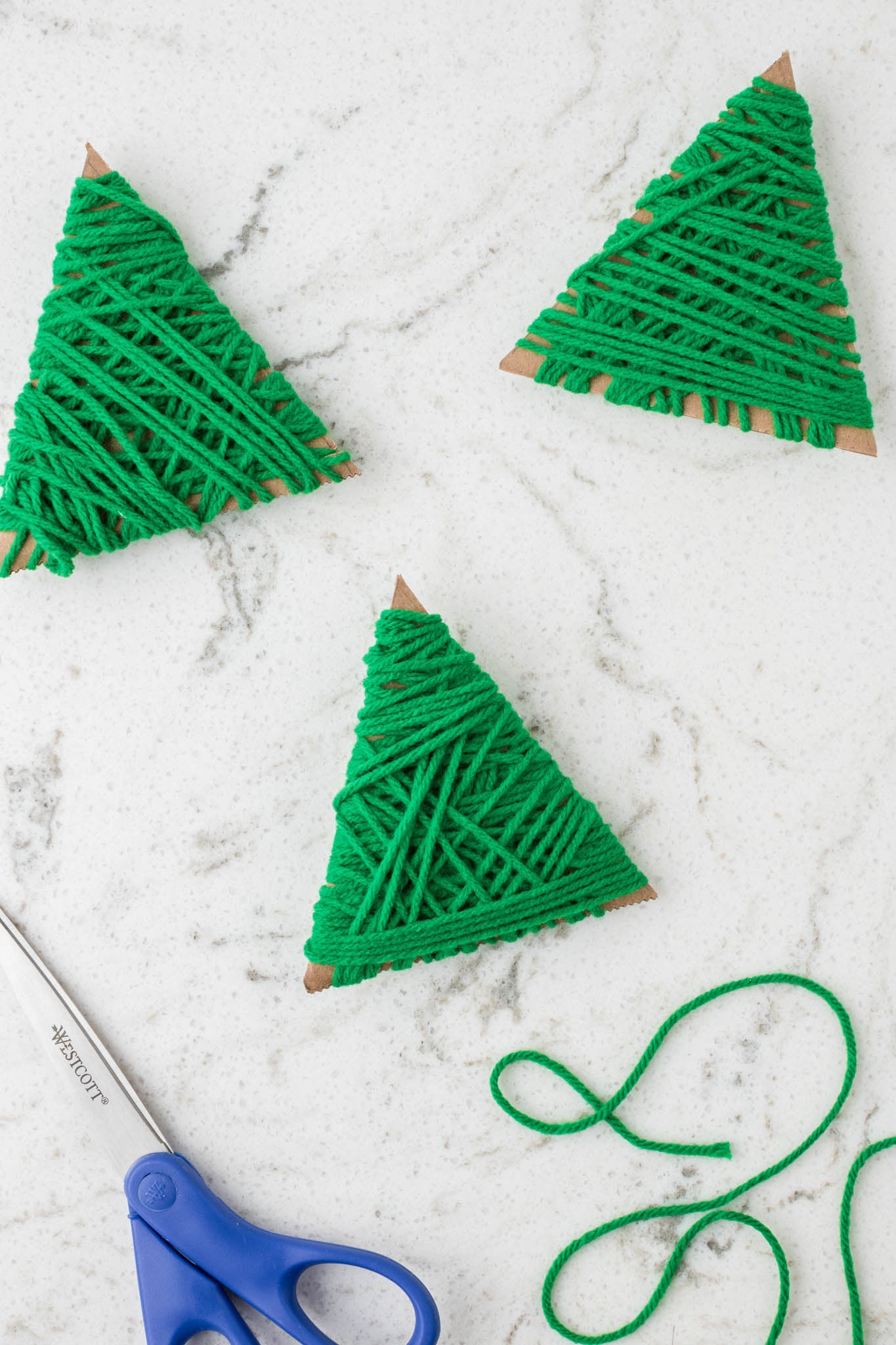 Overhead picture of 3 cardboard triangles wrapped in green yarn.
