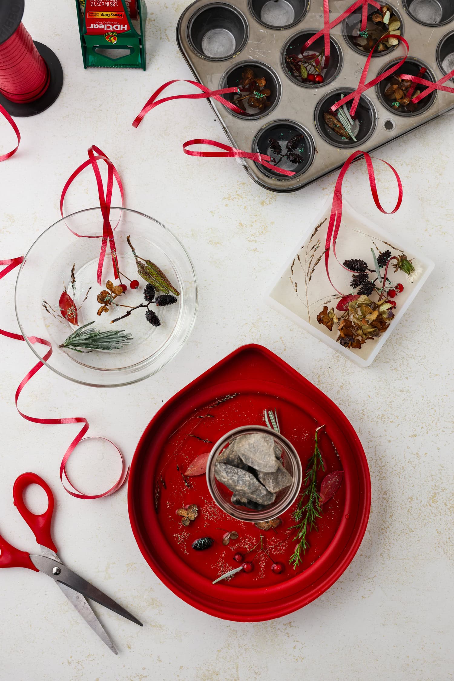 Overhead picture of nature supplies, water, and ribbon in 3 separate containers and in muffin tins.