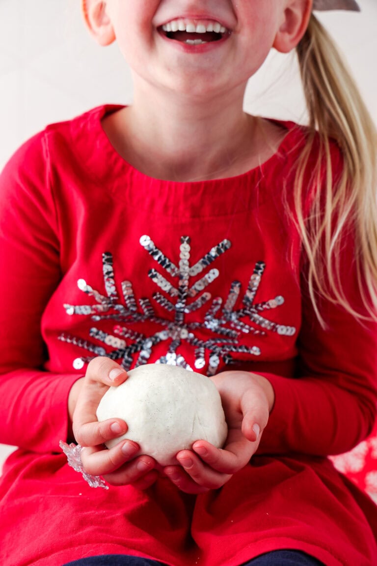 Picture of a girl holding a ball of snow dough.
