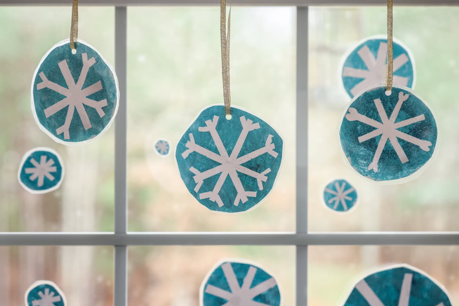 Landscape picture of completed snowflakes hung up in the window.