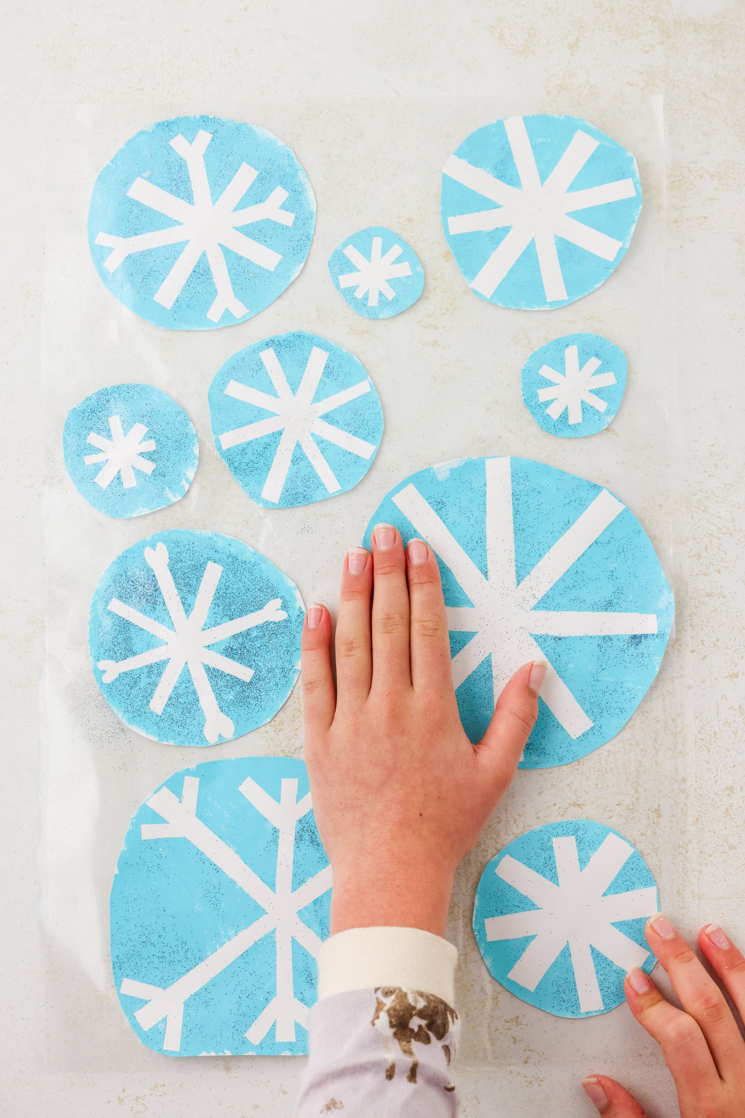 Overhead picture of snowflakes being pressed between the two sheets of contact paper.