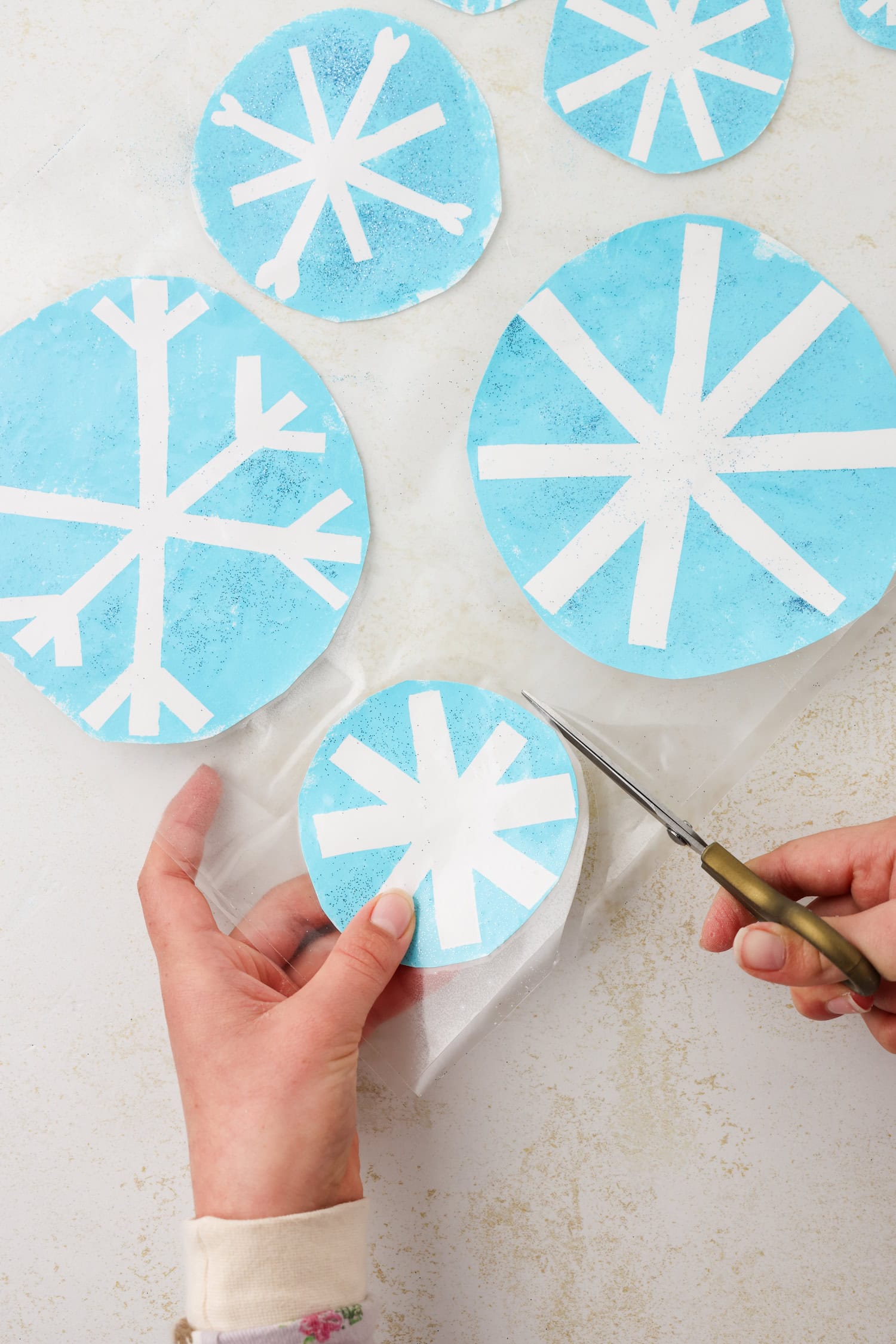 Overhead picture of the snowflake craft being cut out on the contact paper.