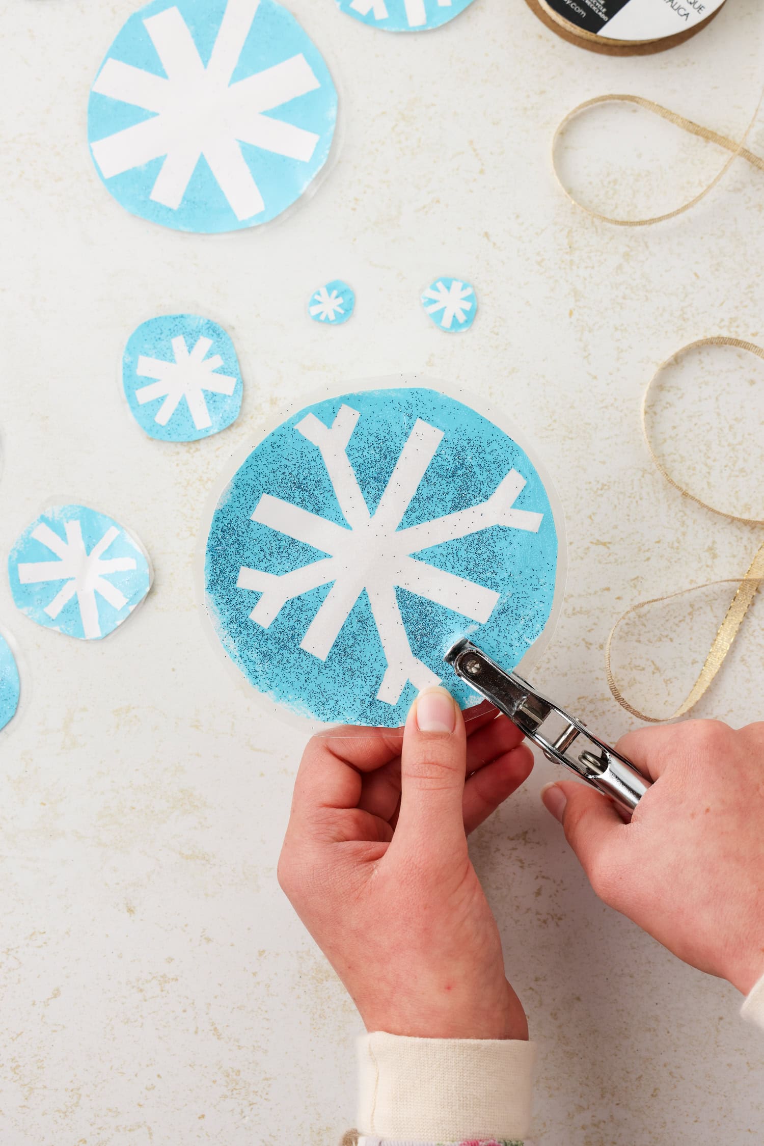 Overhead picture of a hole being hole punched in snowflake craft.