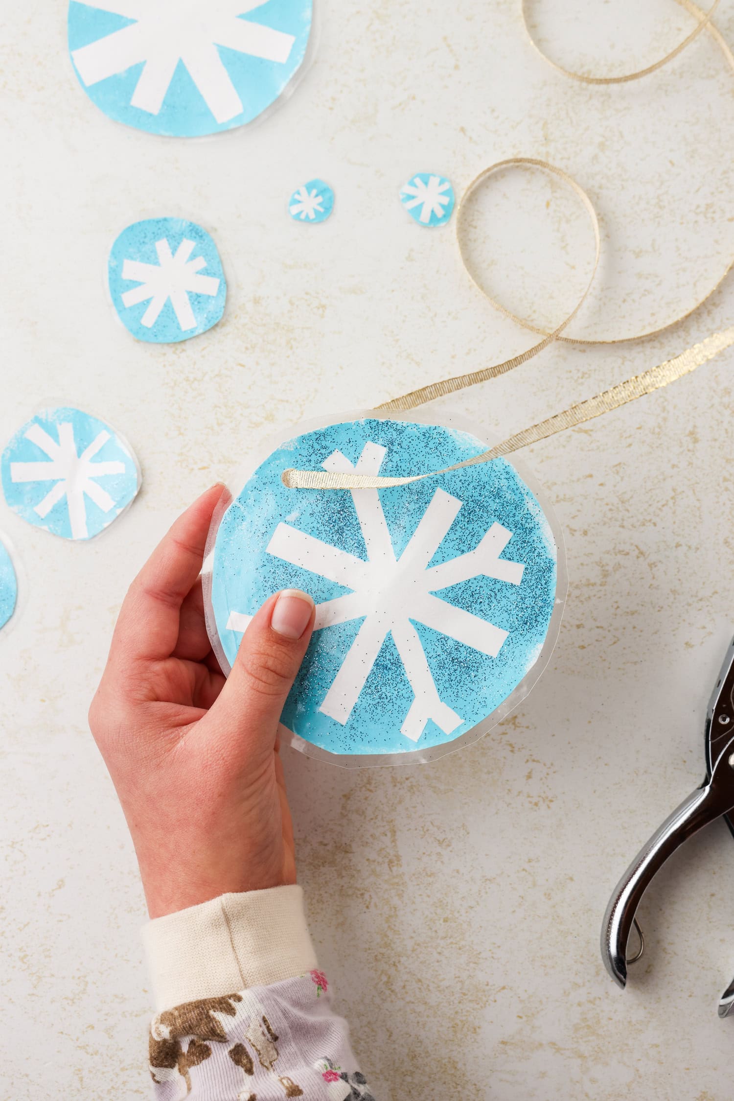 Overhead picture of ribbon being strung through completed snowflake craft.