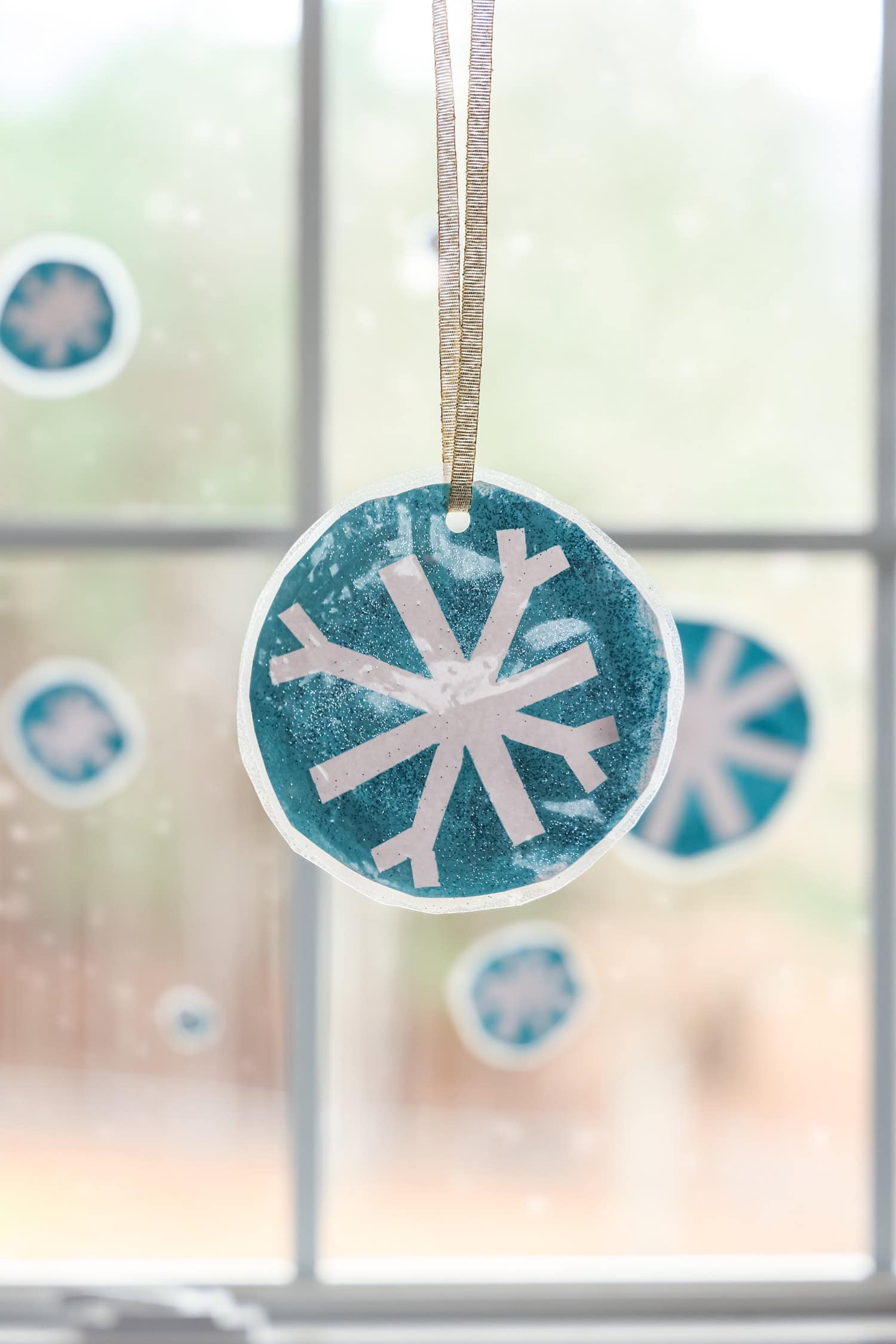 Portrait image of completed snowflake craft hung up in window.