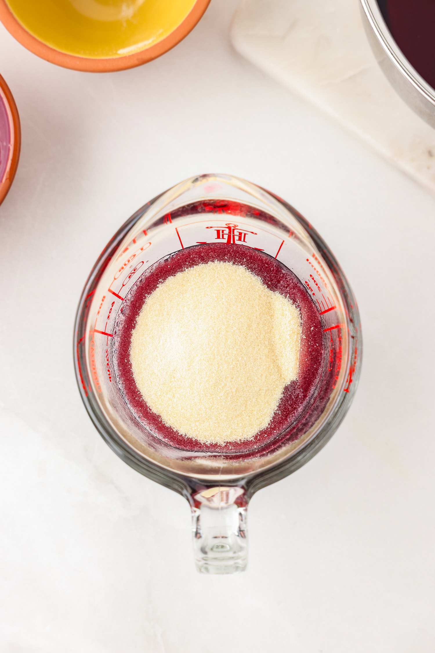 Picture of purple gummy bear ingredient in a glass measuring cup unmixed.
