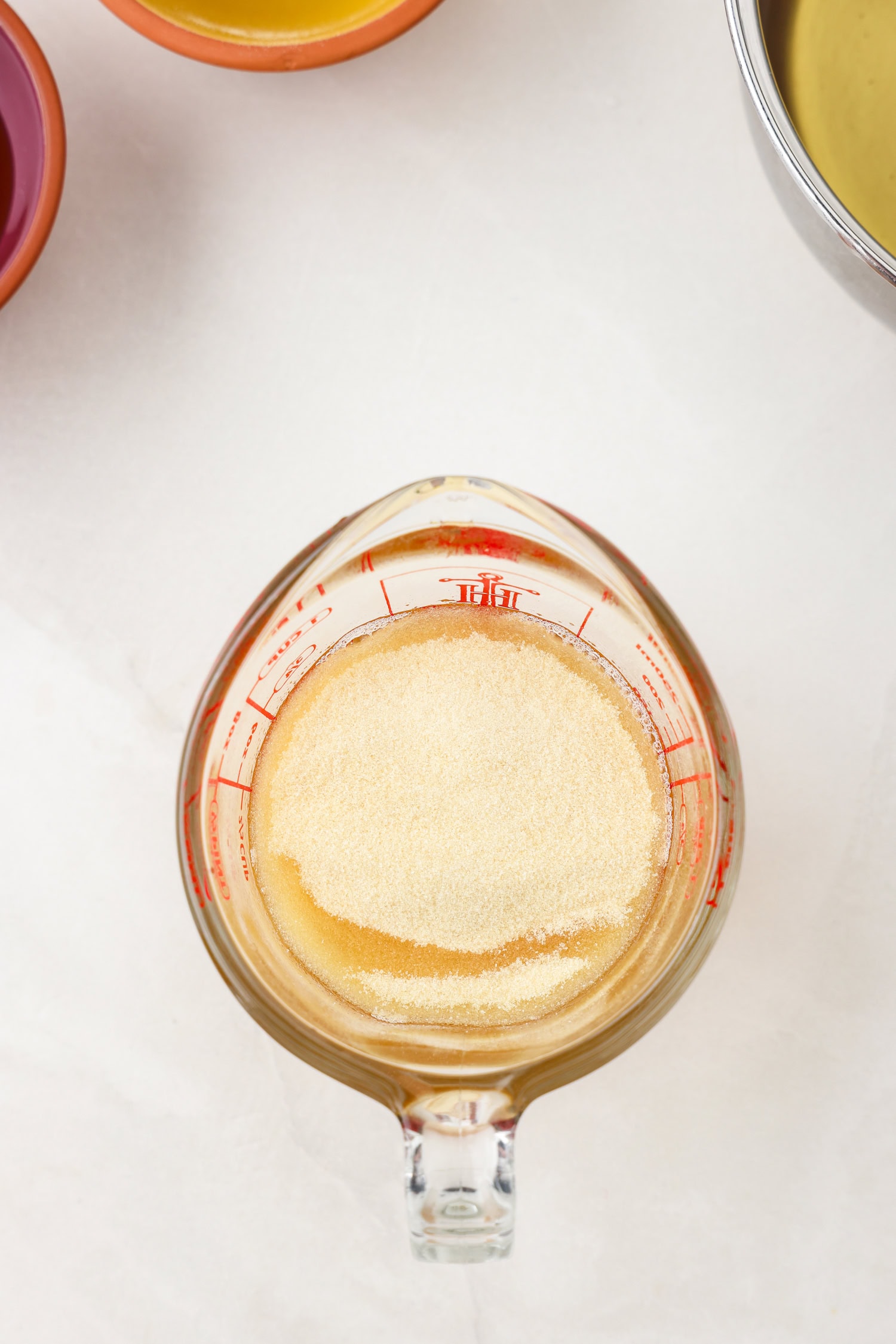 Picture of apple juice gummy bear ingredient in a glass measuring cup unmixed.