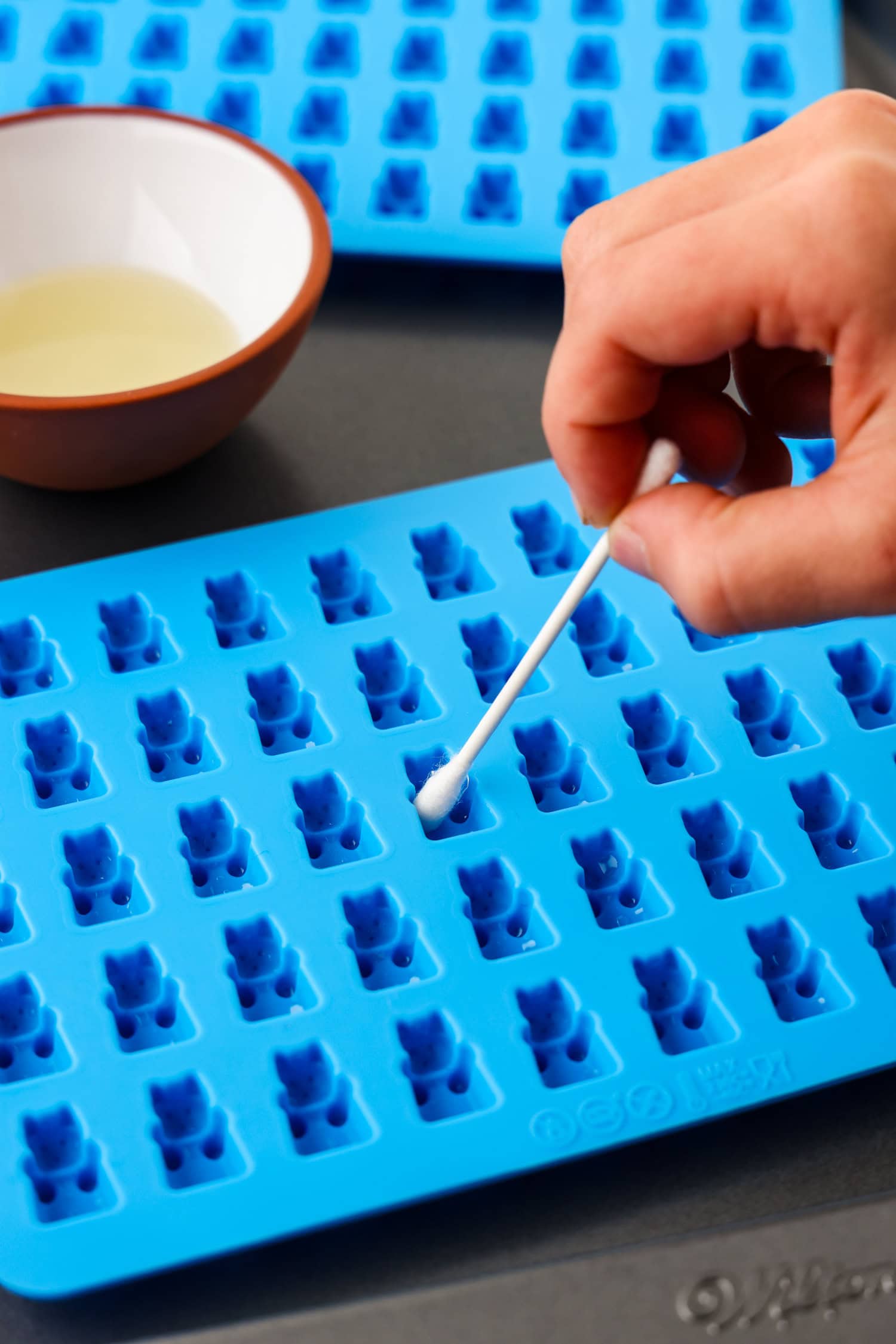 Hand using q tip inside fruit snack molds.