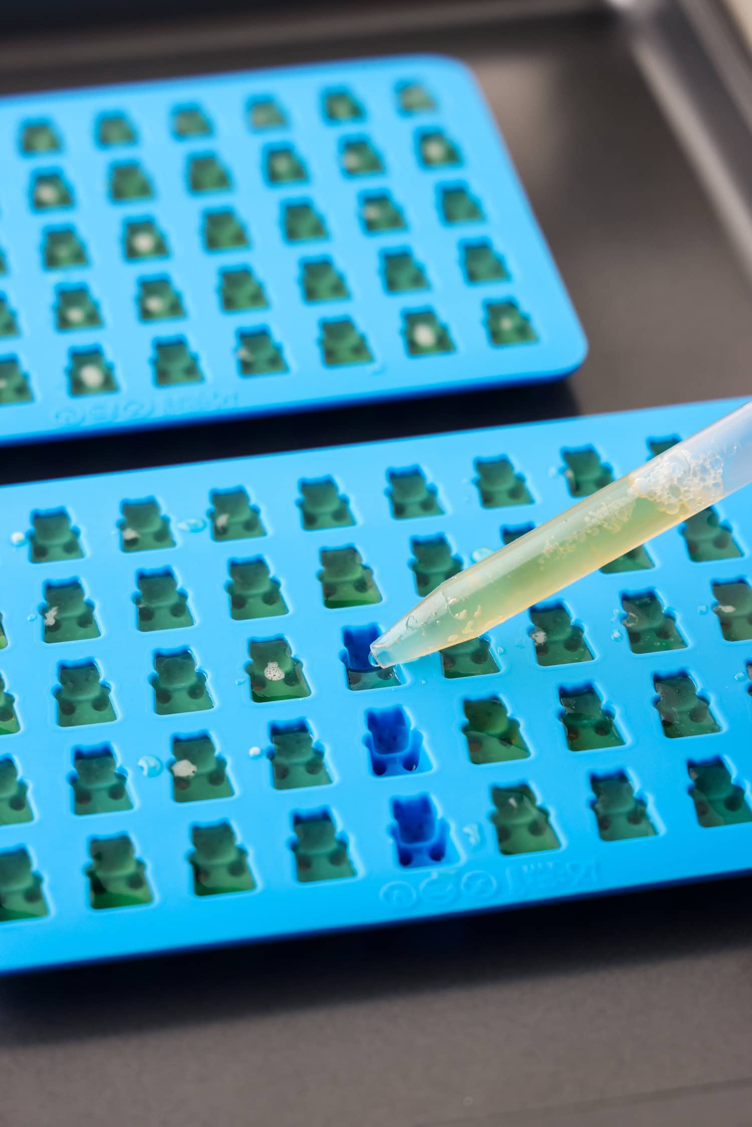 Picture of dropper putting clear juice into gummy bear molds.