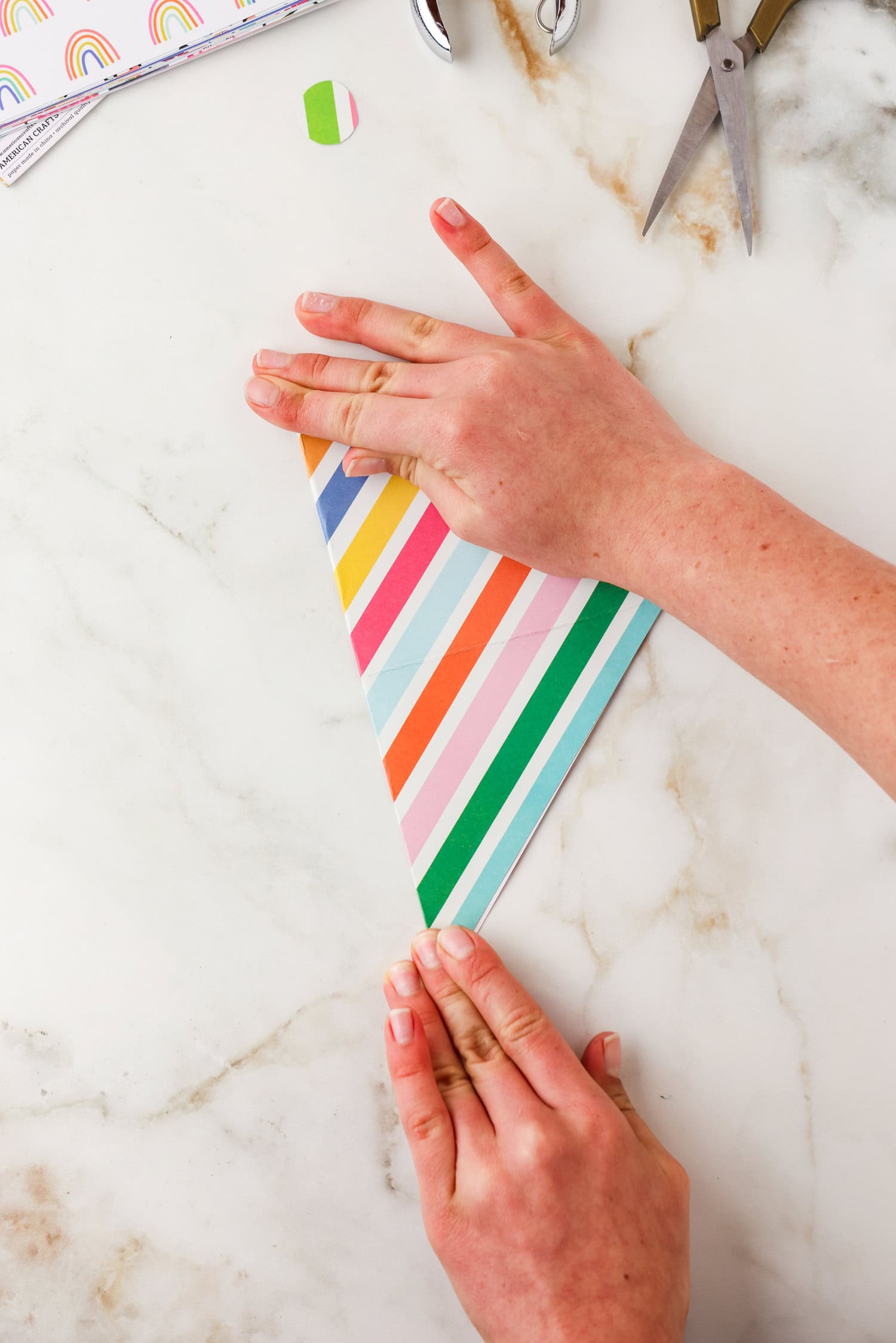 Hands pressing down on the crease of the fold.