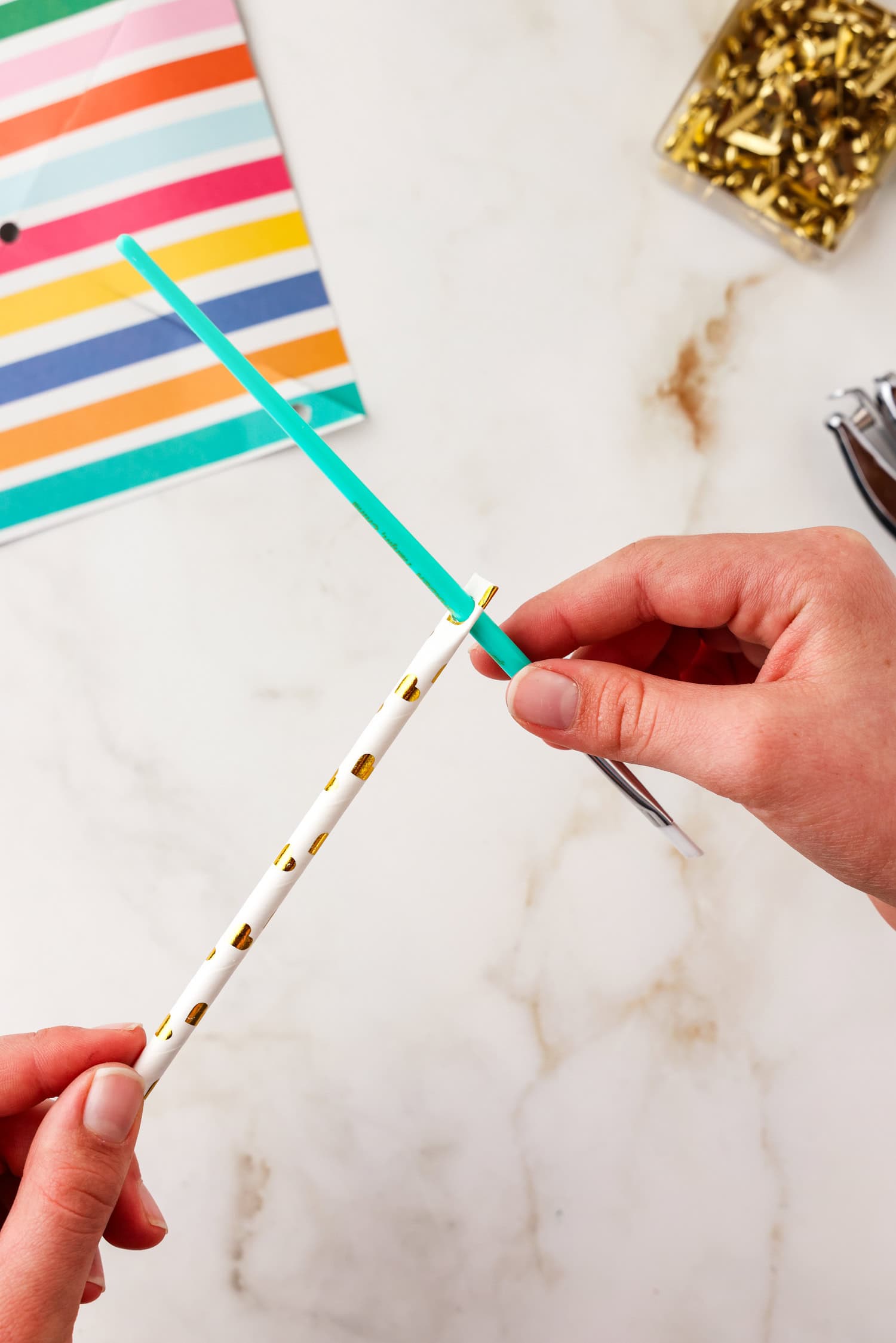 Paper straw with hole on the end and paintbrush pushed through it.