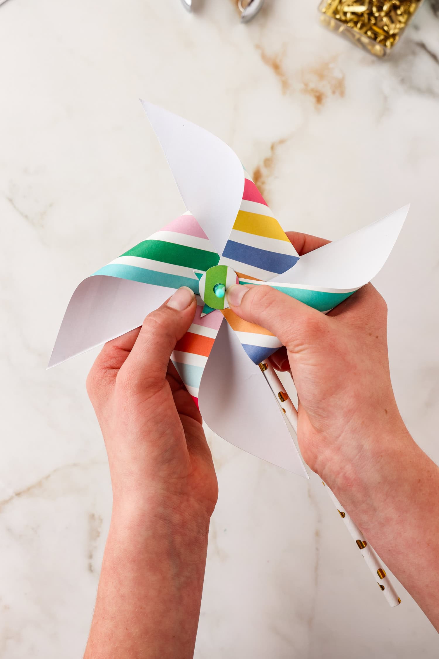 Small circle with hole in center being placed in the center of the pinwheel on the paint brush.