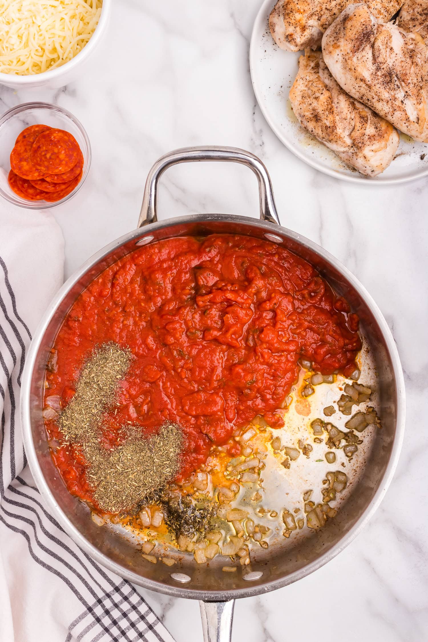 Overhead picture of pizza chicken sauce ingredients in a pan unmixed.