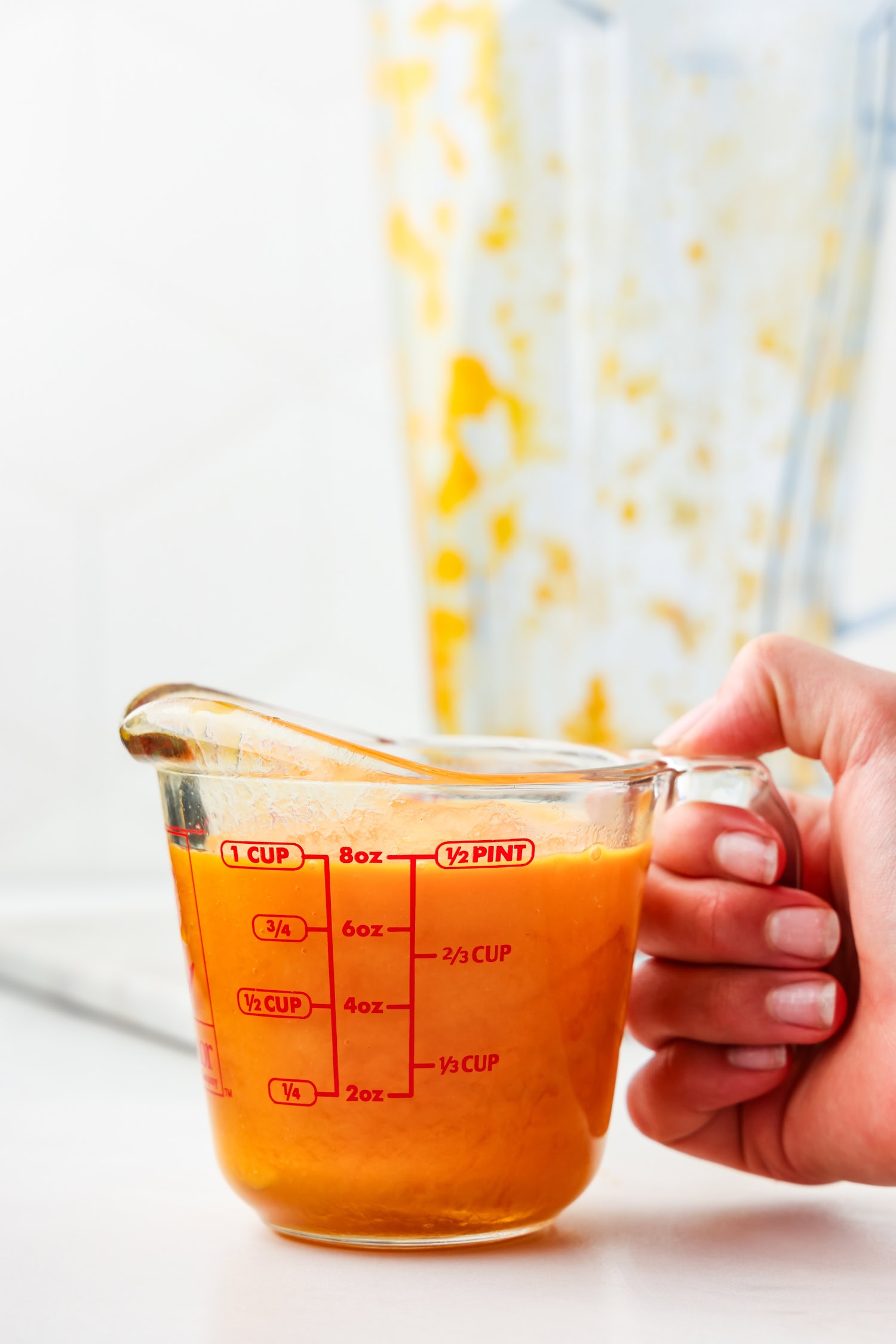 Orange fruit mixture blended in glass measuring cup.