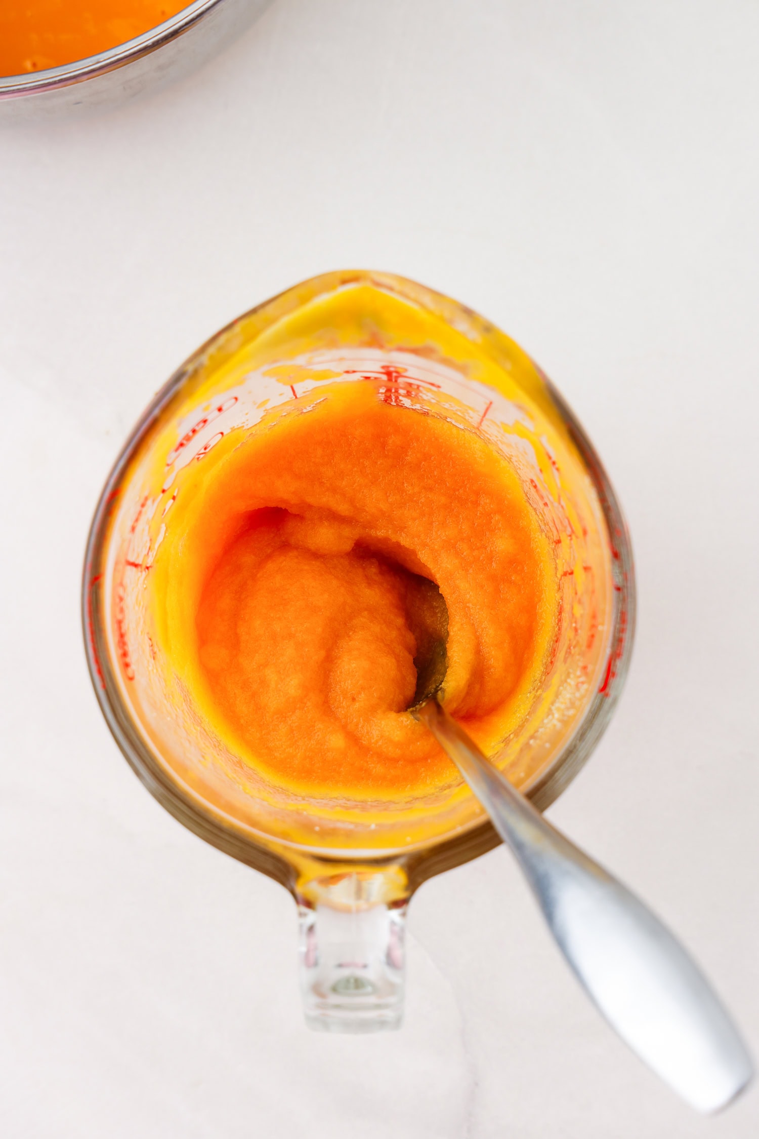 Orange fruit mixture blended in glass measuring cup with gelatin mixed.