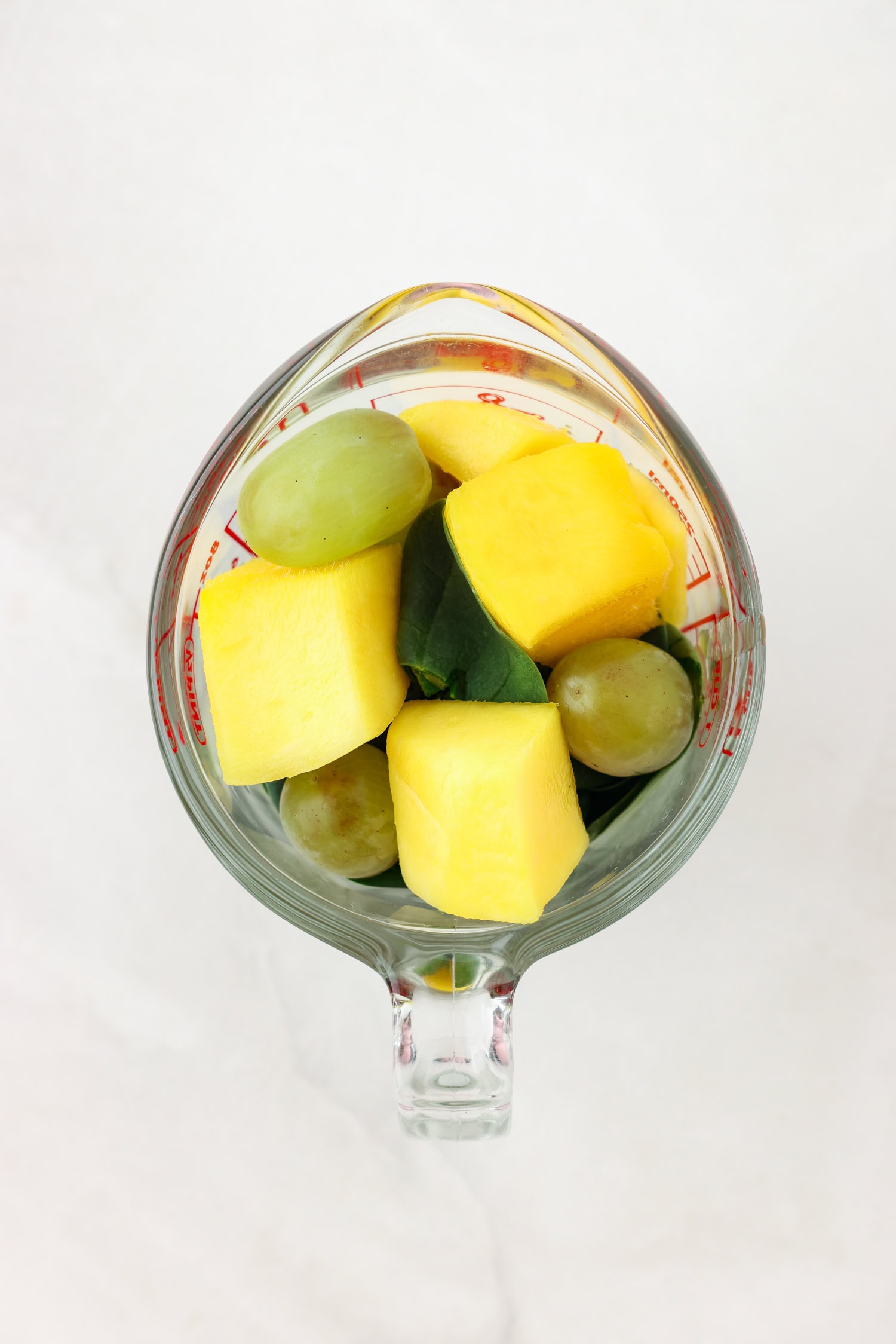 Overhead picture of green fruit mixture in a measuring glass.