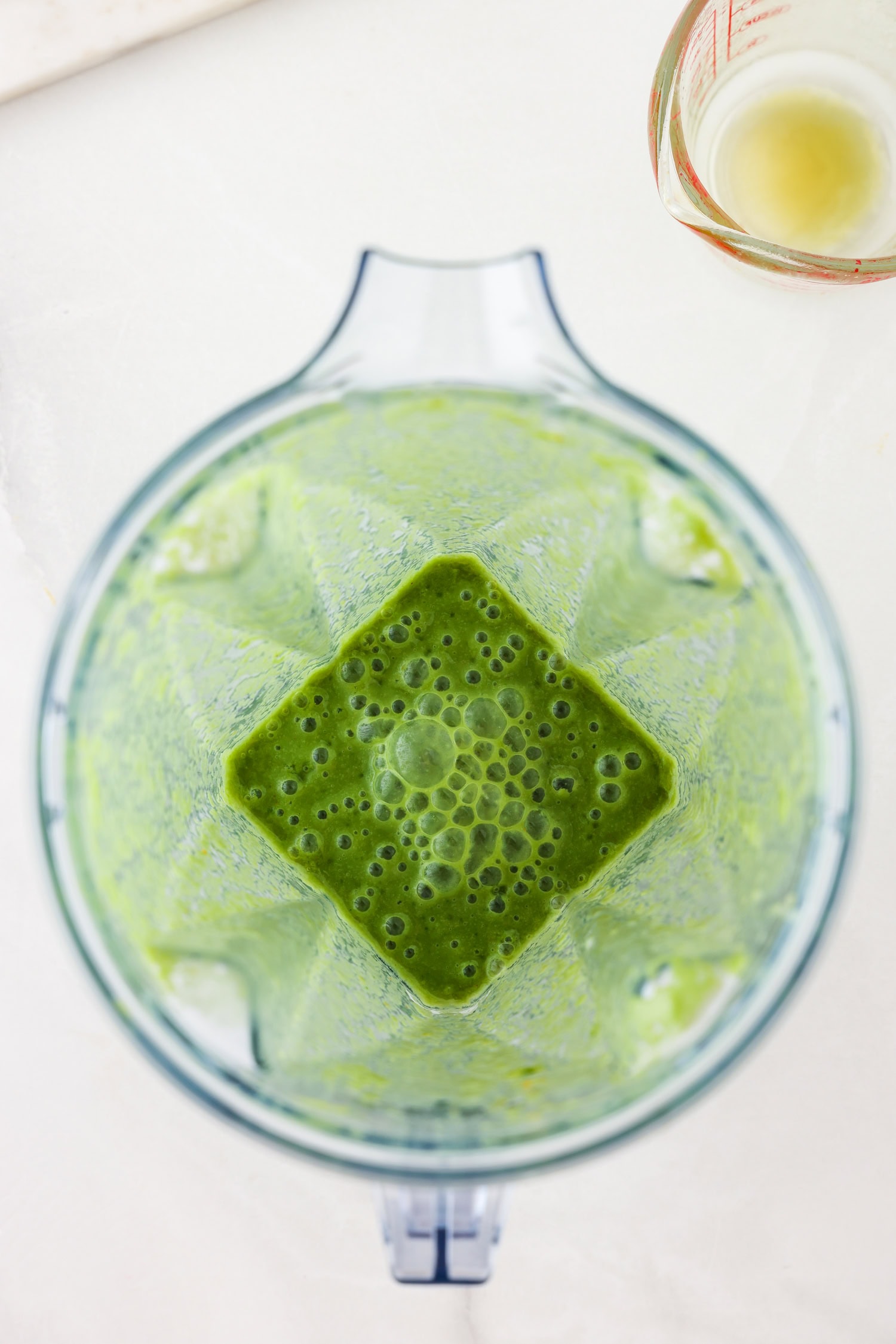 Green fruit mixture in a blender blended together.