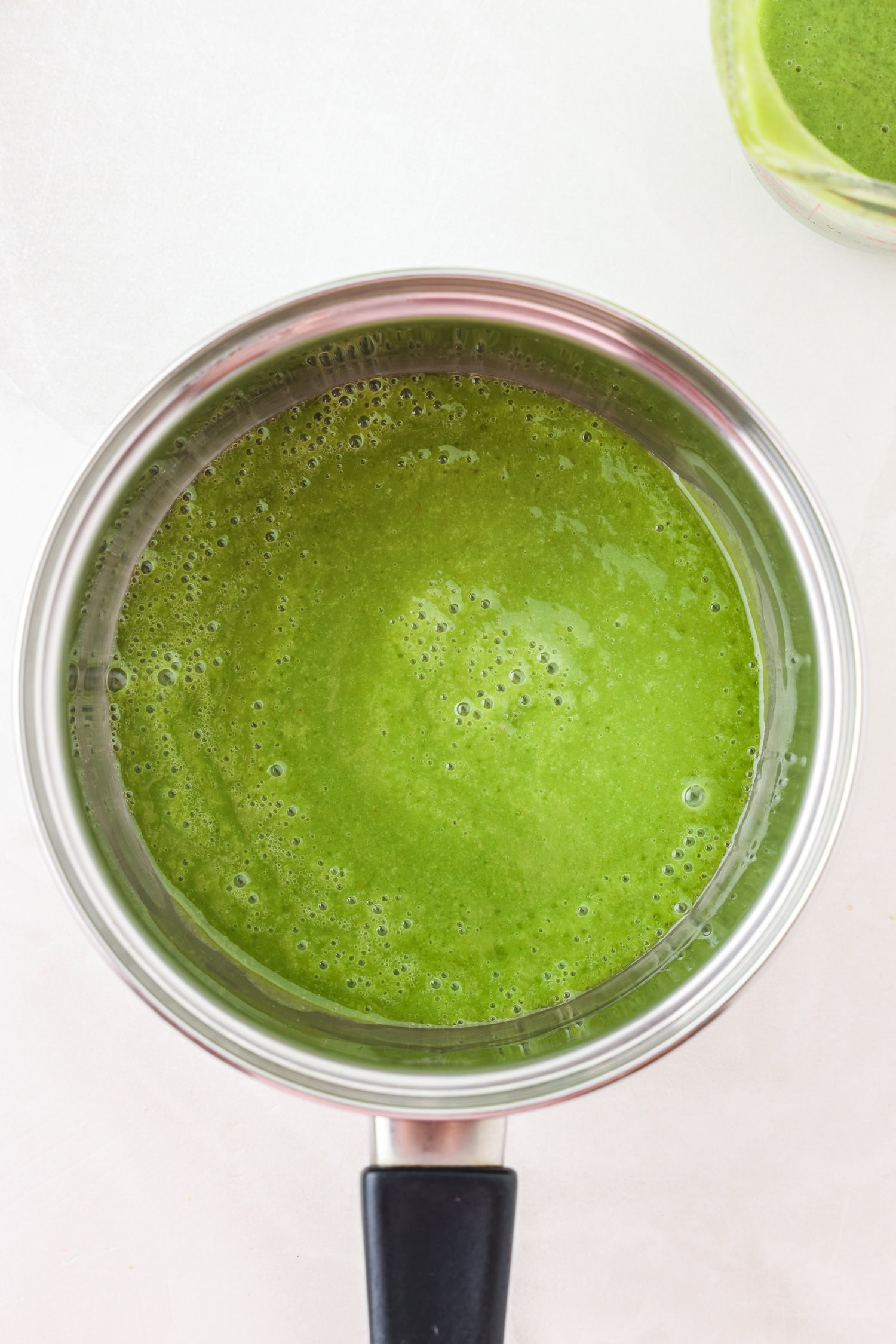 Green fruit mixture blended in a sauce pan.