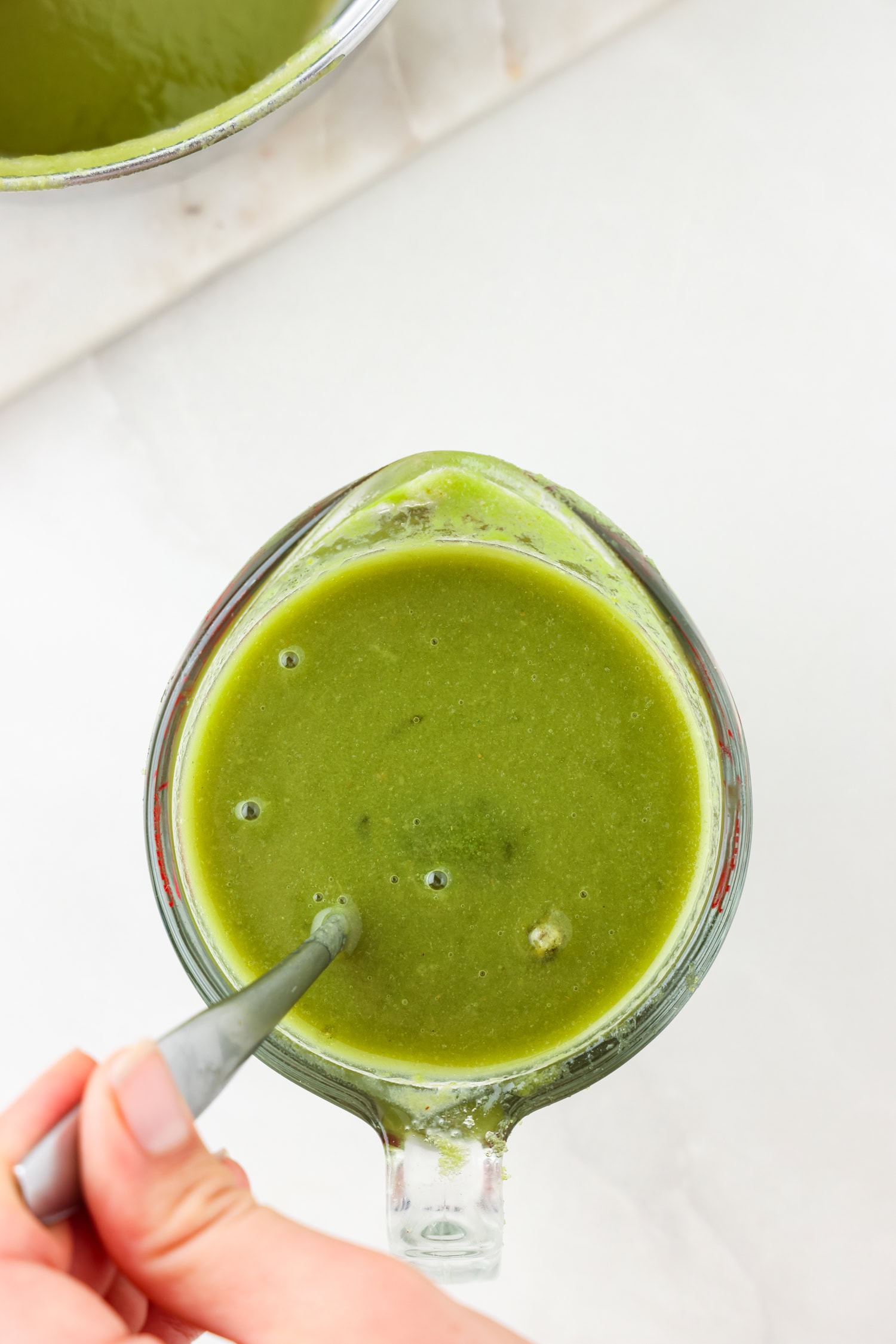 Green fruit mixture blended in a glass measuring cup.