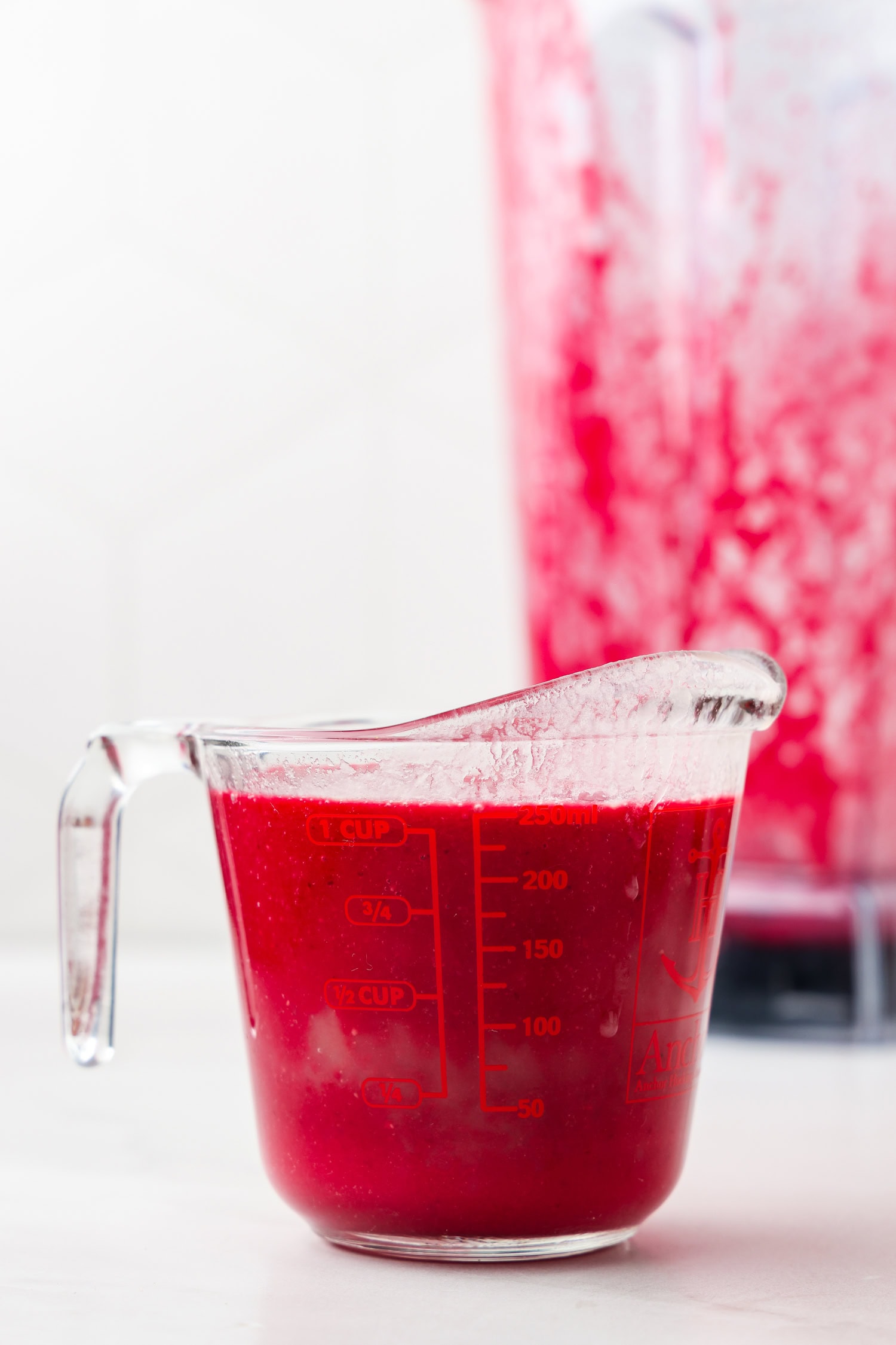 Red fruit mixture blended in a glass measuring cup.