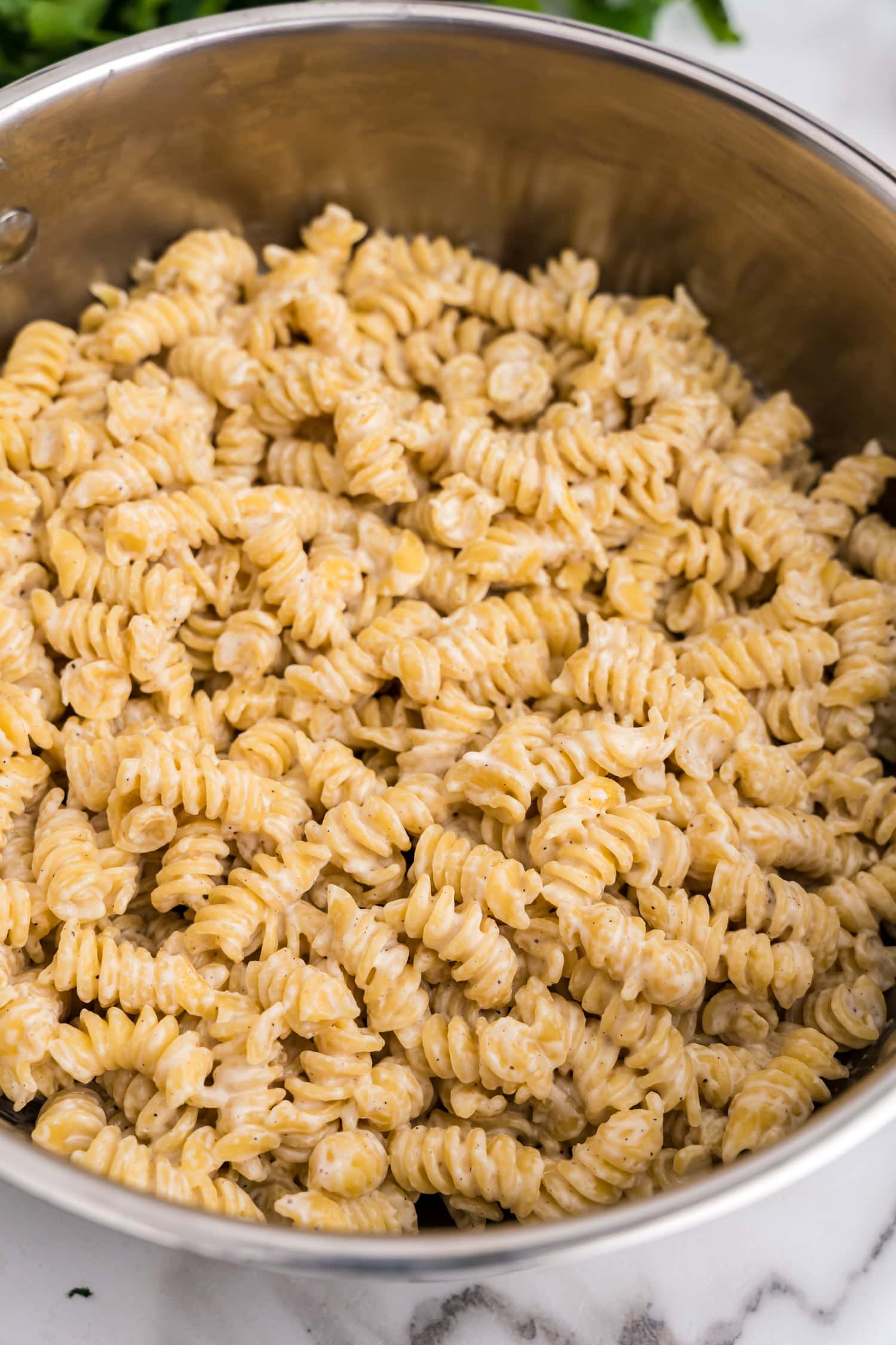 Close-up view of creamy rotini pasta in a pot, highlighting the smooth, rich cheese coating each noodle.
