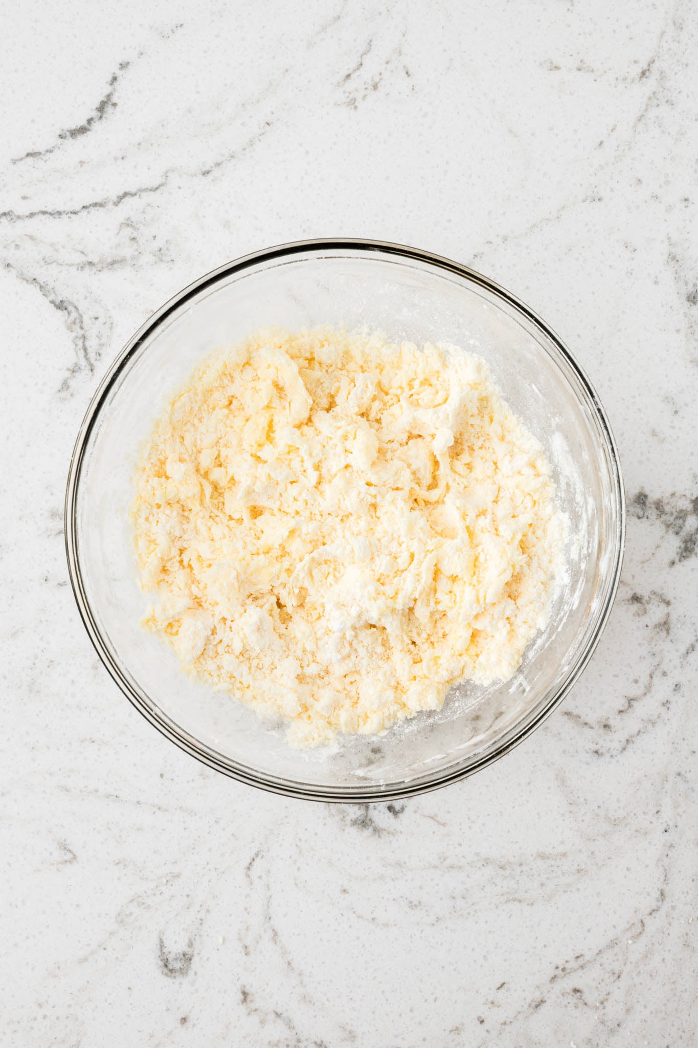 The bowl now contains a partially mixed yellow and white crumbly mixture, indicating the initial mixing of dry and wet ingredients.