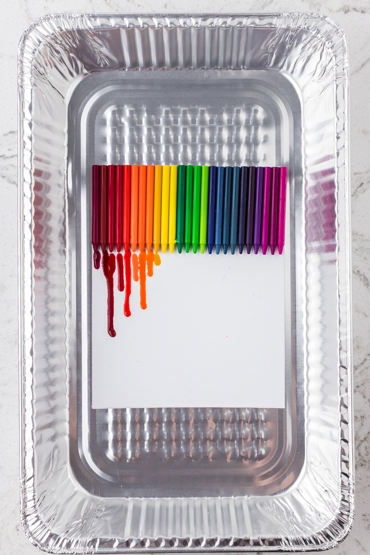 The first signs of melting appear, with red and orange crayon wax beginning to drip down the canvas.