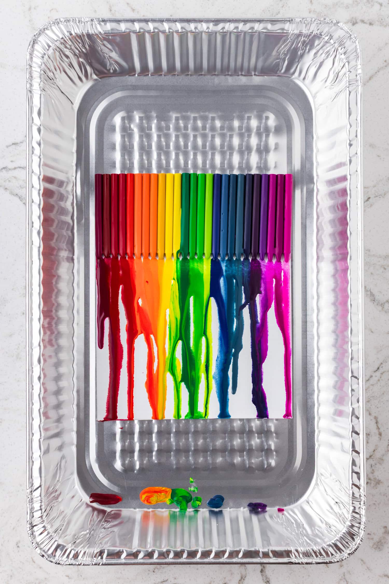 A nearly complete melt with full rainbow drips covering much of the canvas. The tray bottom catches wax puddles.