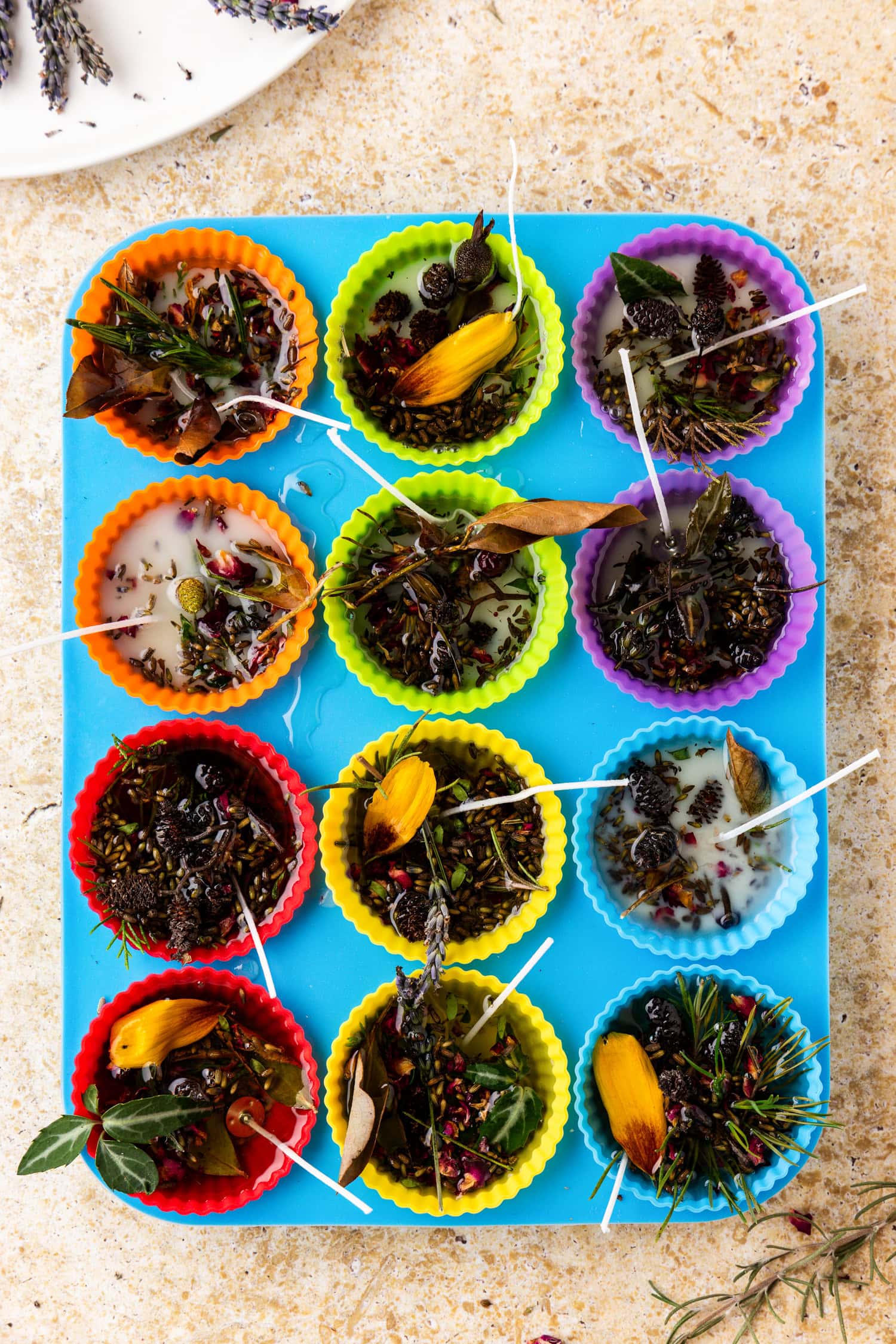 All the silicone liners are filled with wax and have wicks inserted. The wax is starting to solidify, and the herbs and flowers are suspended within.