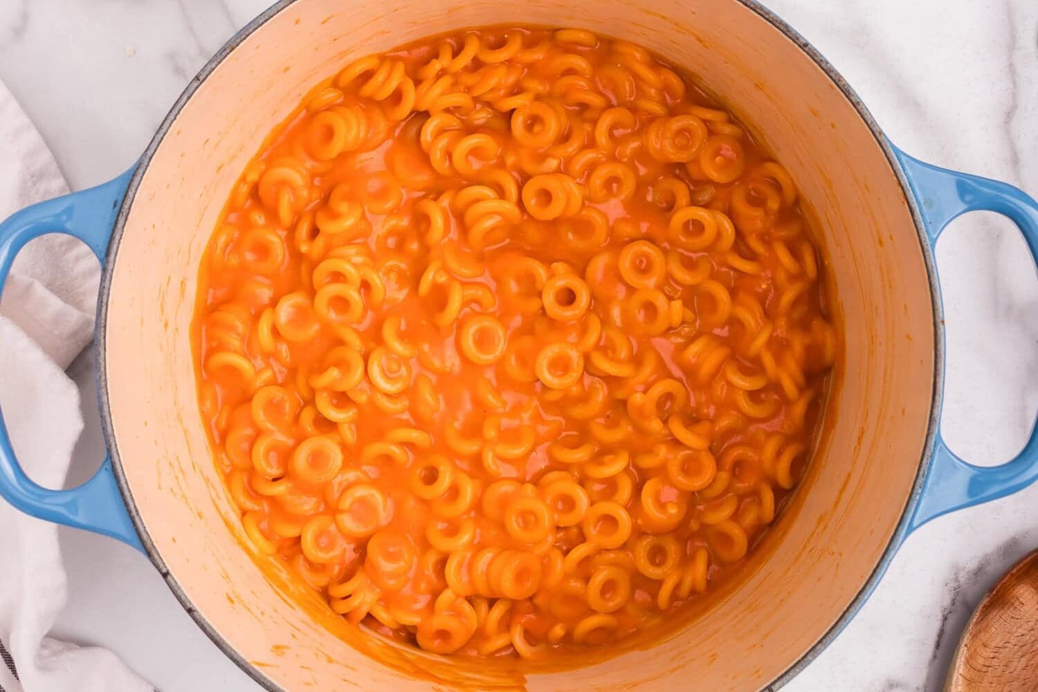 The Dutch oven filled with creamy tomato-coated pasta rings, fully cooked and well-mixed.