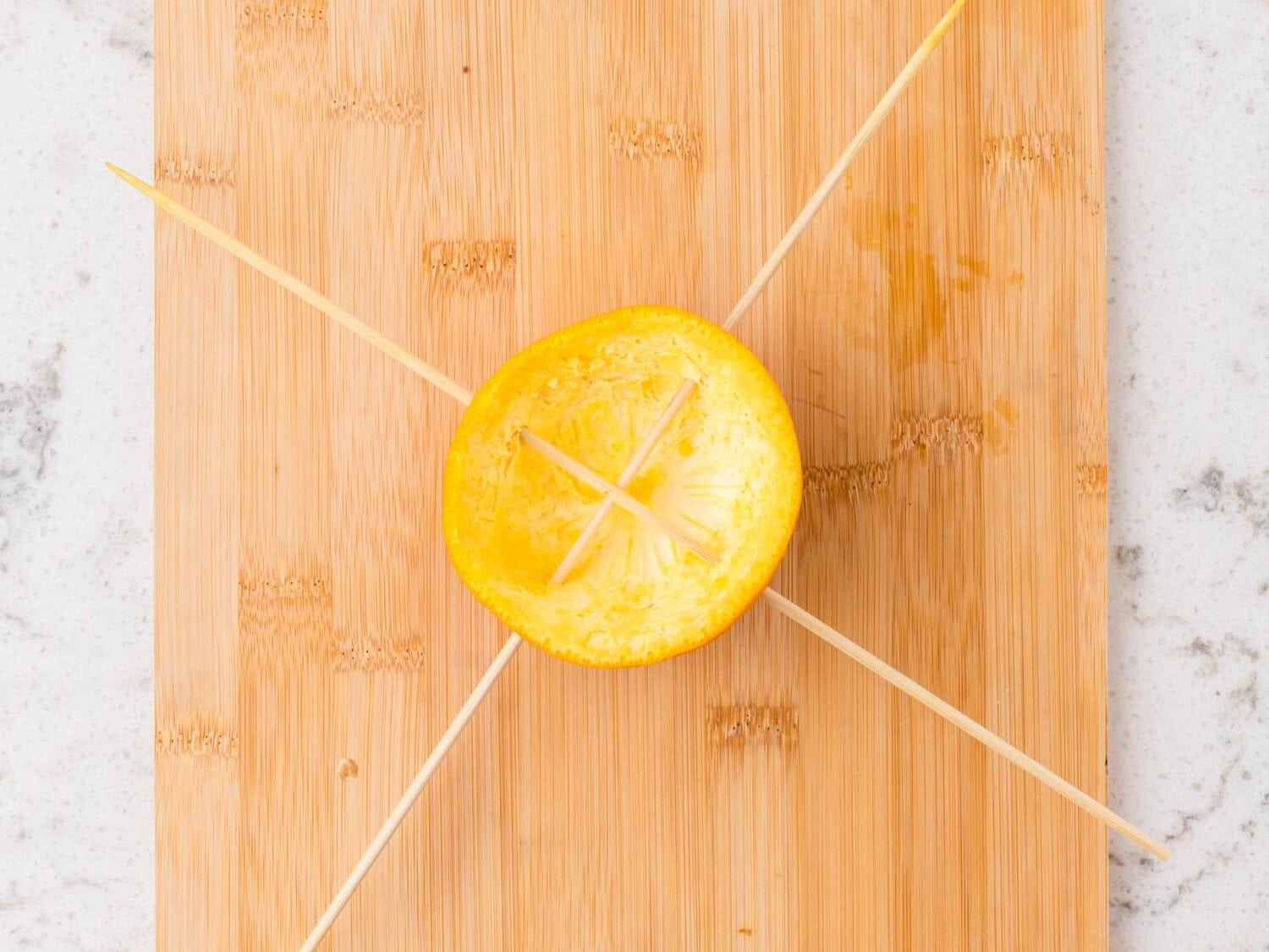 Wooden skewers pushed through the orange rind in a crisscross pattern to form a perch.