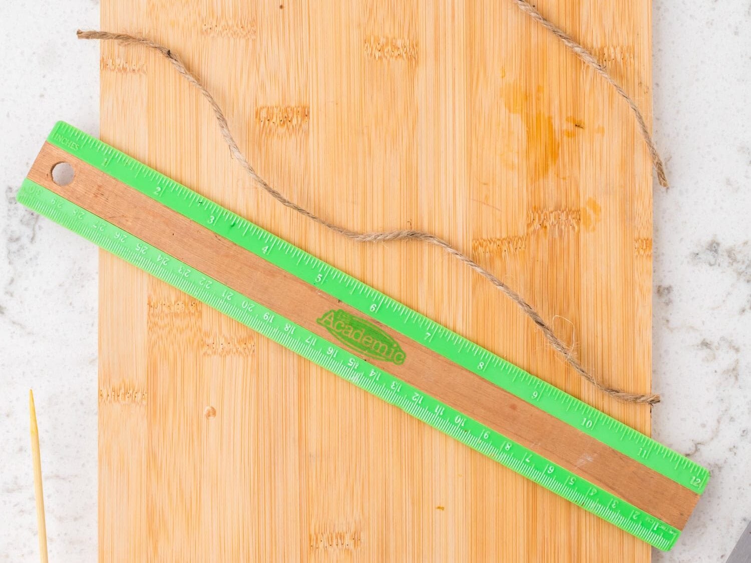 A length of twine measured with a ruler on a wooden cutting board.
