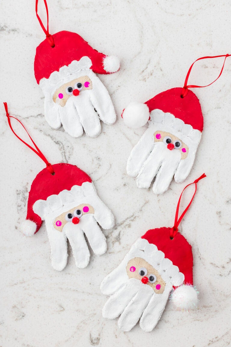 Four finished Santa handprint ornaments painted red and white with red ribbons for hanging.