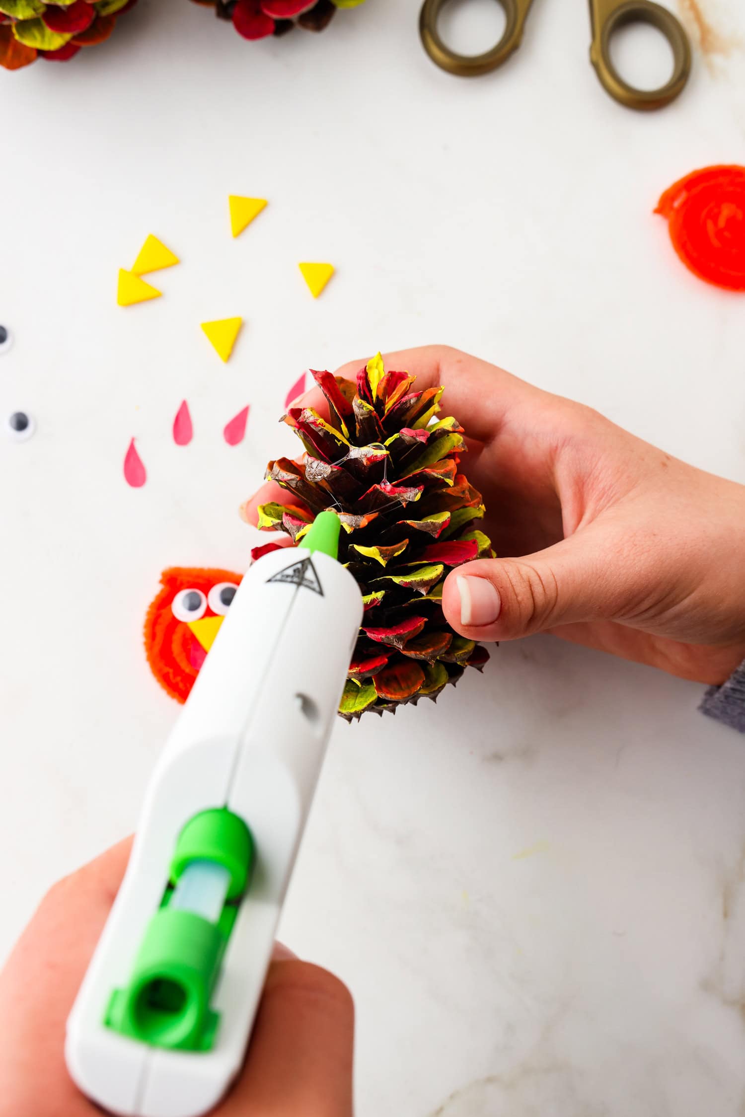 Picture of glue being placed onto pinecone for face.