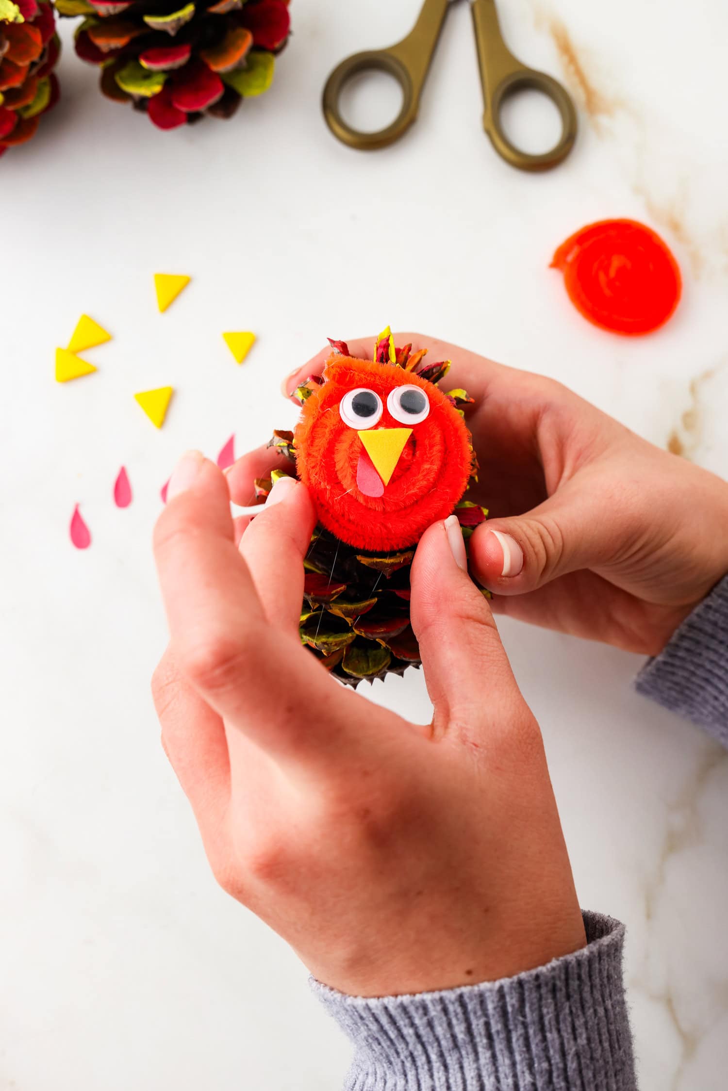 Picture of turkey face being glued onto pinecone.