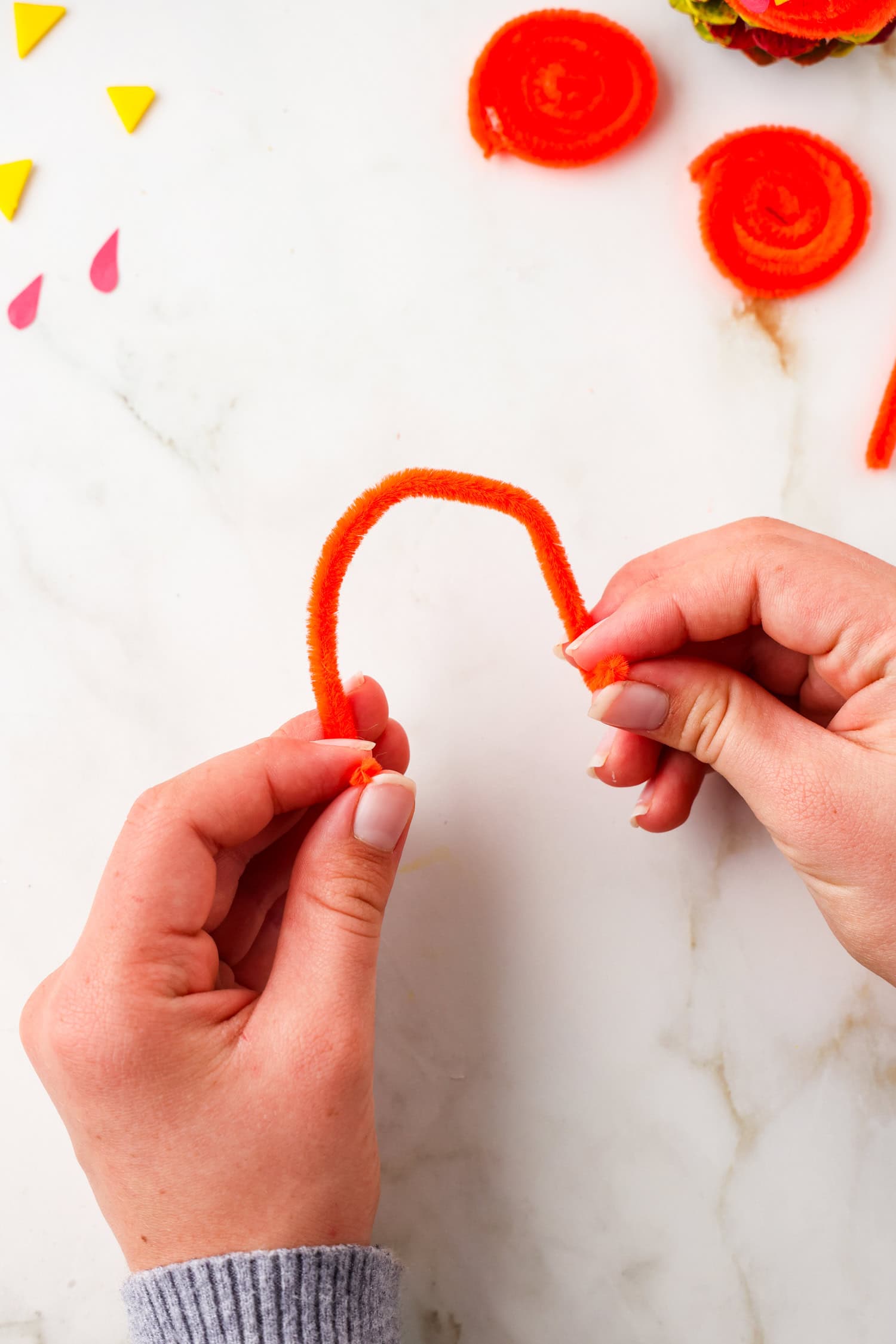 Picture of red pipecleaner being bent in half.